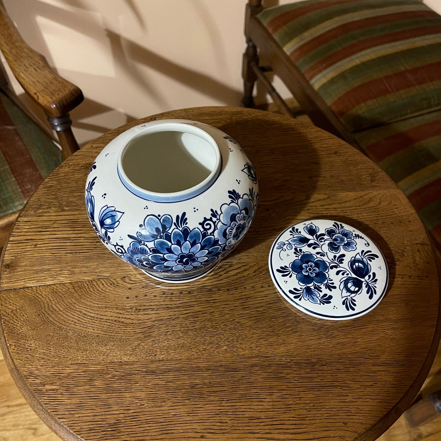 Ceramic jar and lid with blue floral patterns on a wooden table.
