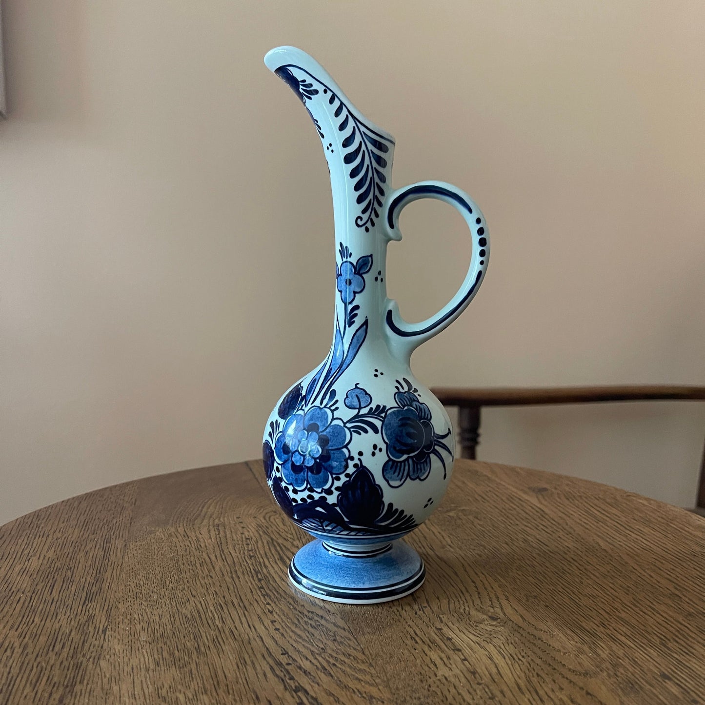 Blue and white ceramic pitcher with floral design on a wooden surface