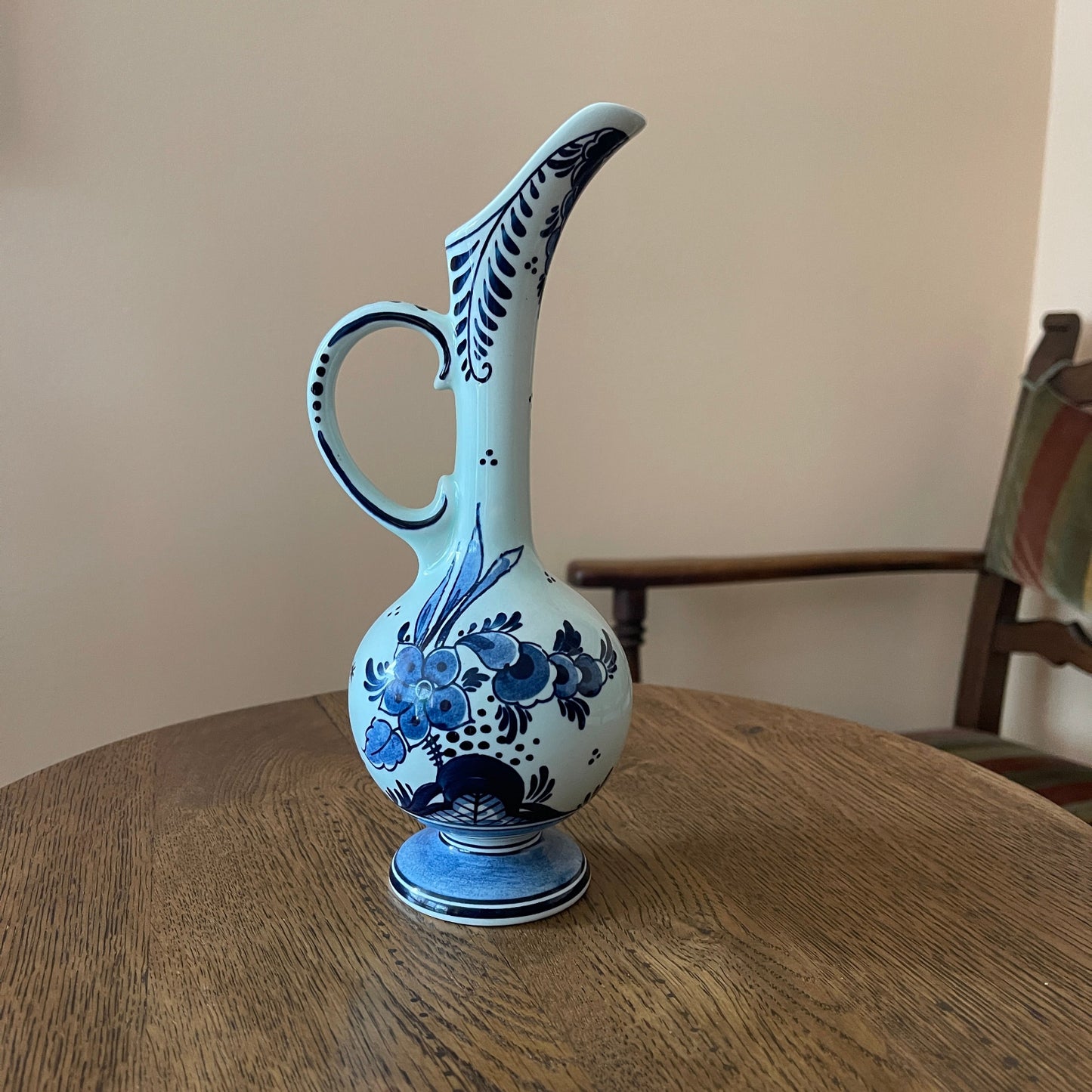 Decorative blue and white pitcher on a wooden table with a neutral background