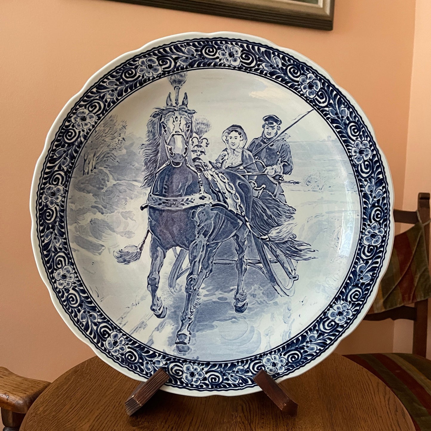 Decorative plate with a horse and rider design on a stand against a beige wall.