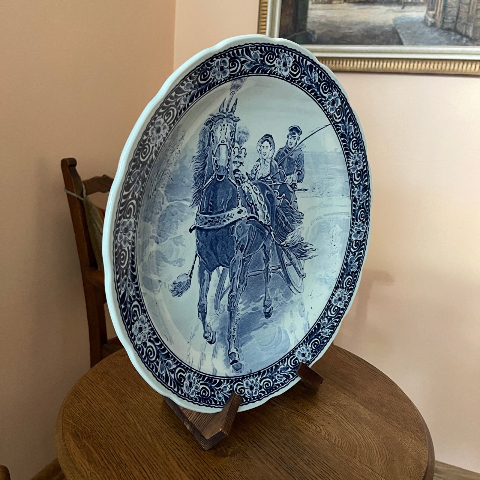 Decorative plate with a horse and rider design on a wooden stand against a beige wall.