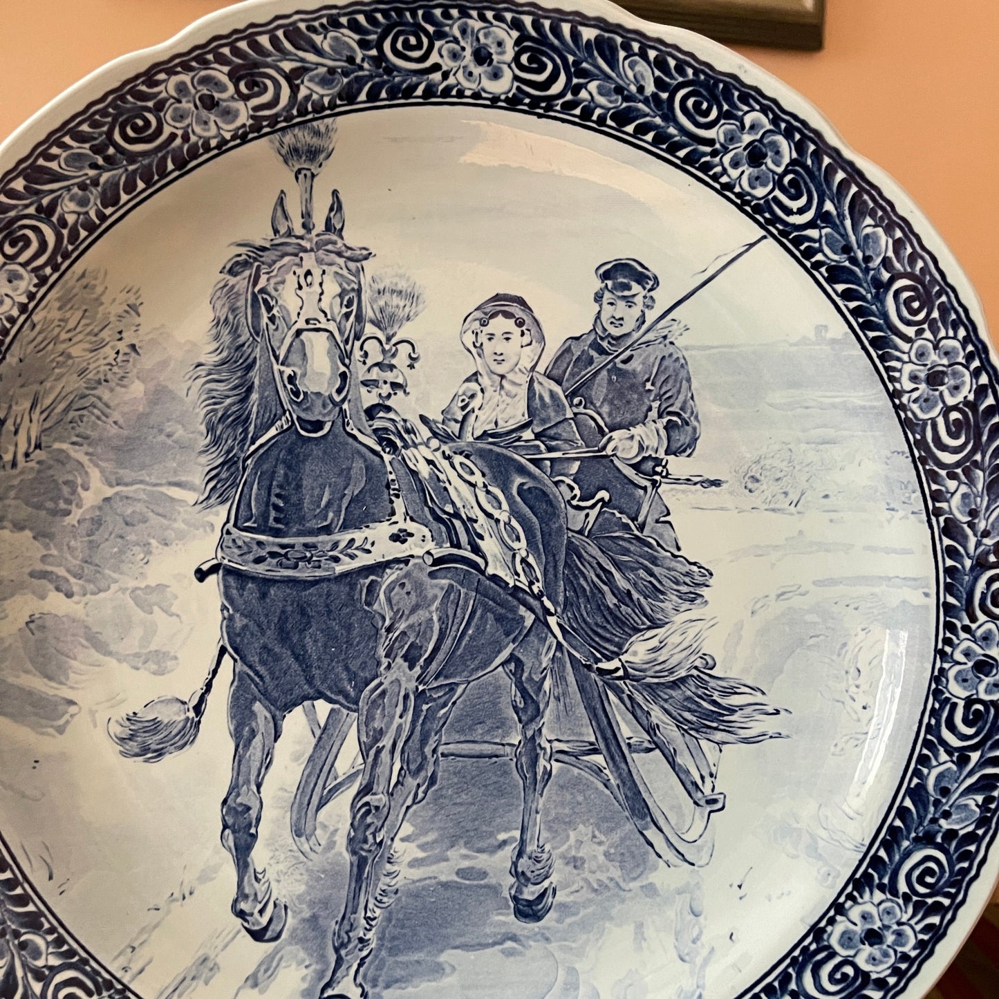 Decorative plate with a black and white illustration of a horse and two people, framed by decorative border.