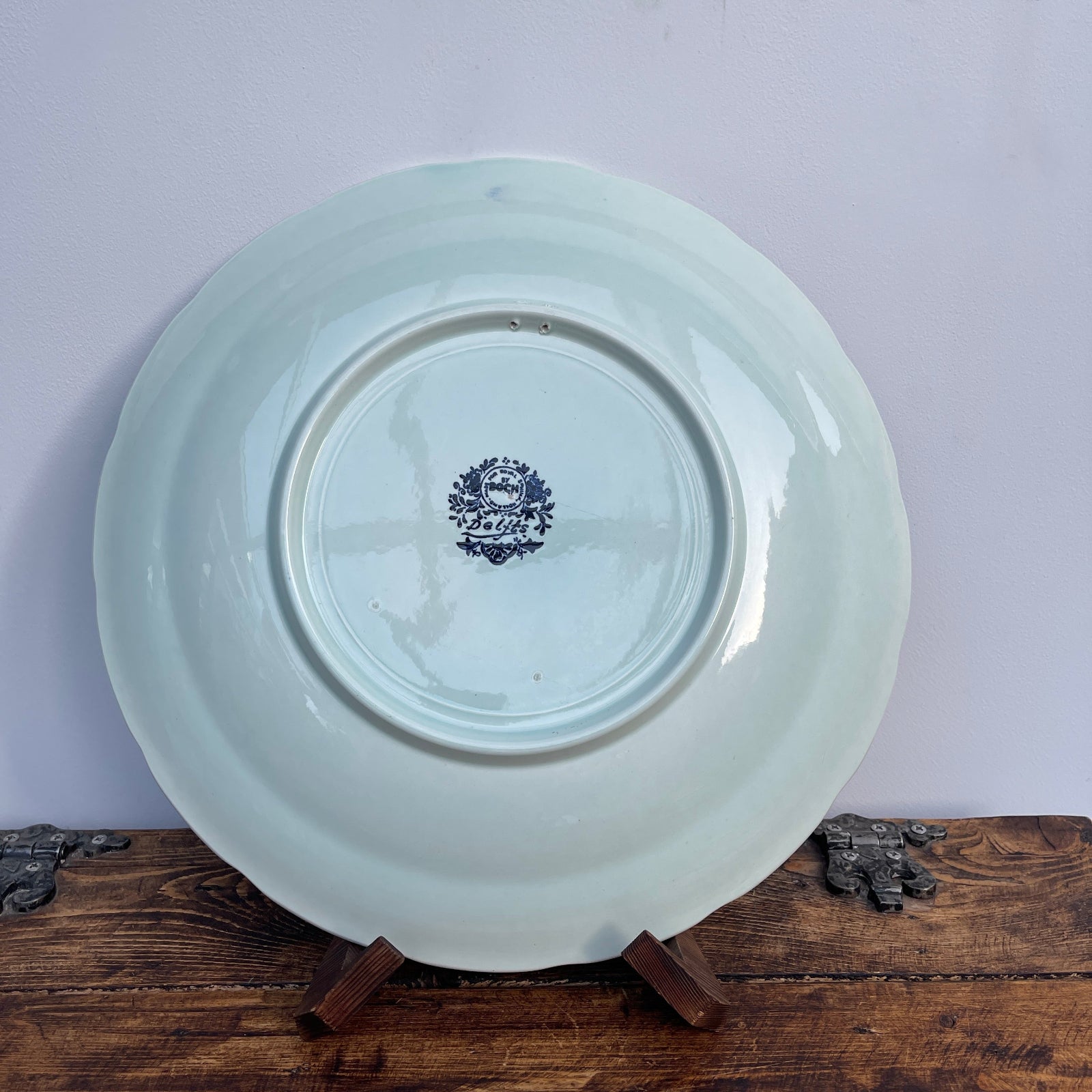 White ceramic plate with a blue emblem on a wooden stand against a white background