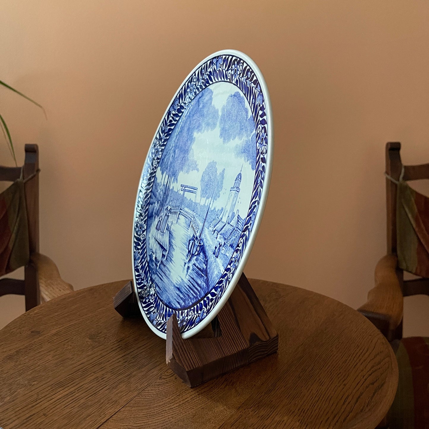 Decorative blue and white plate on a stand against a beige wall.
