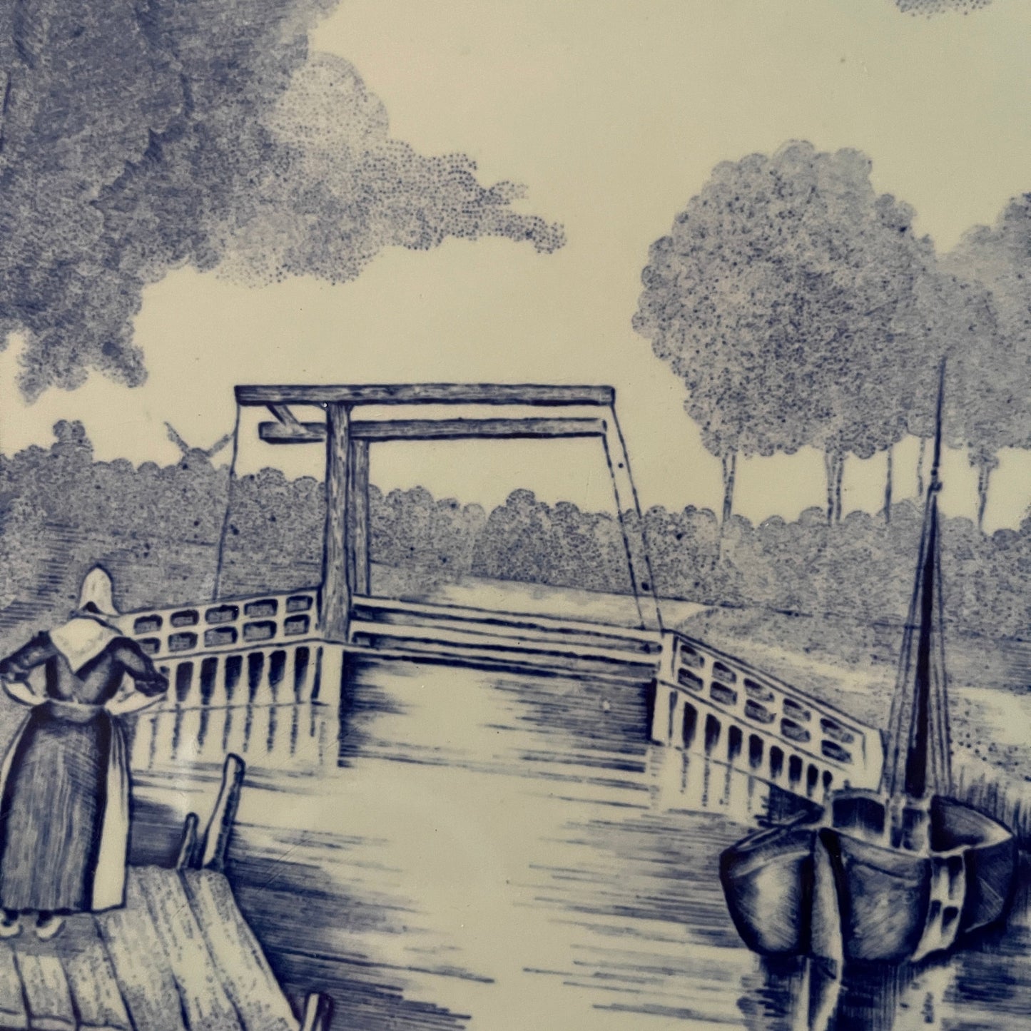Dutch canal scene with a woman on a bridge and boats.