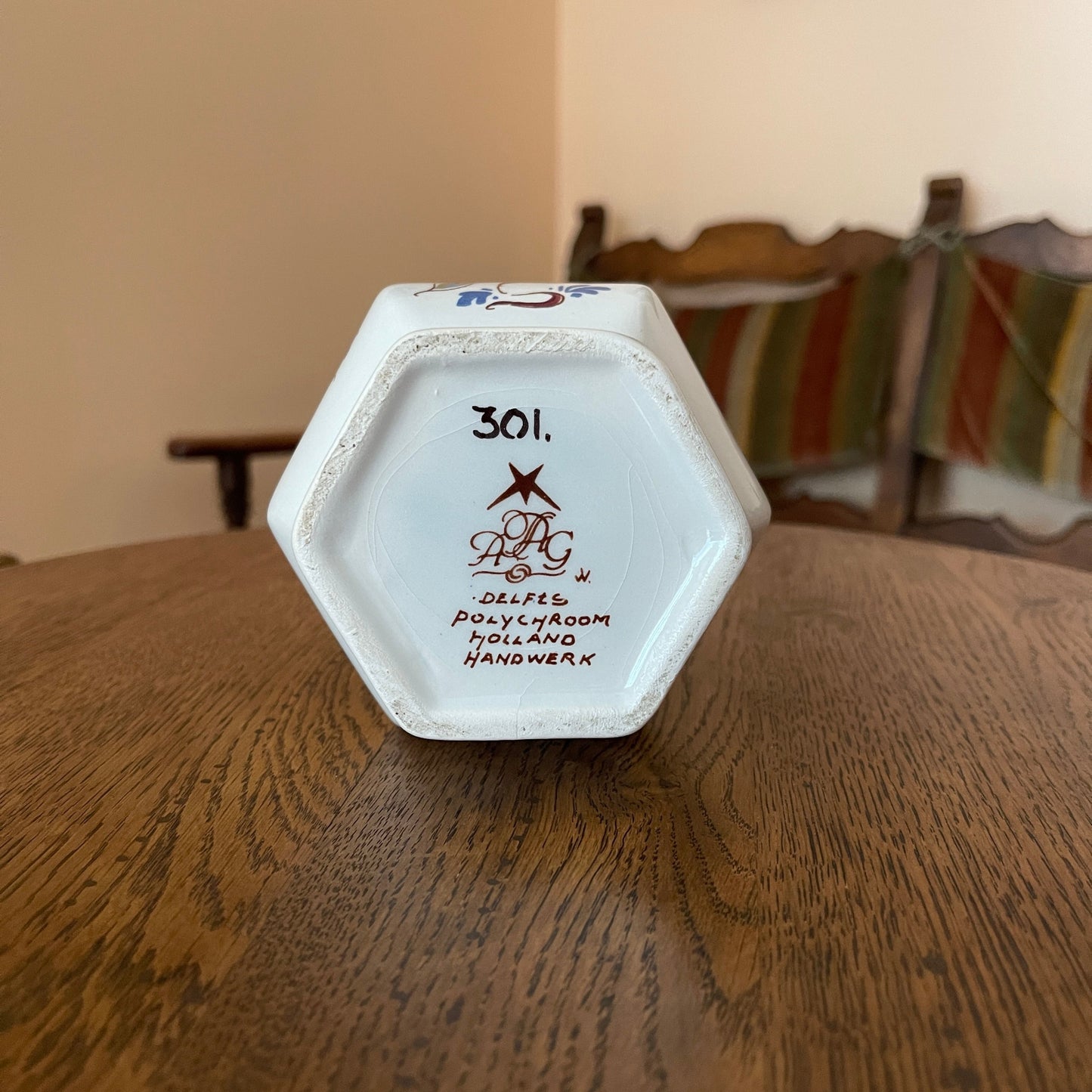 Hexagonal ceramic object with '301' and branding on a wooden surface