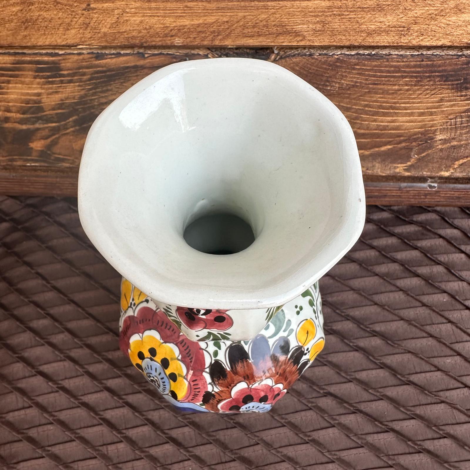 Decorative ceramic vase with floral patterns on a woven surface