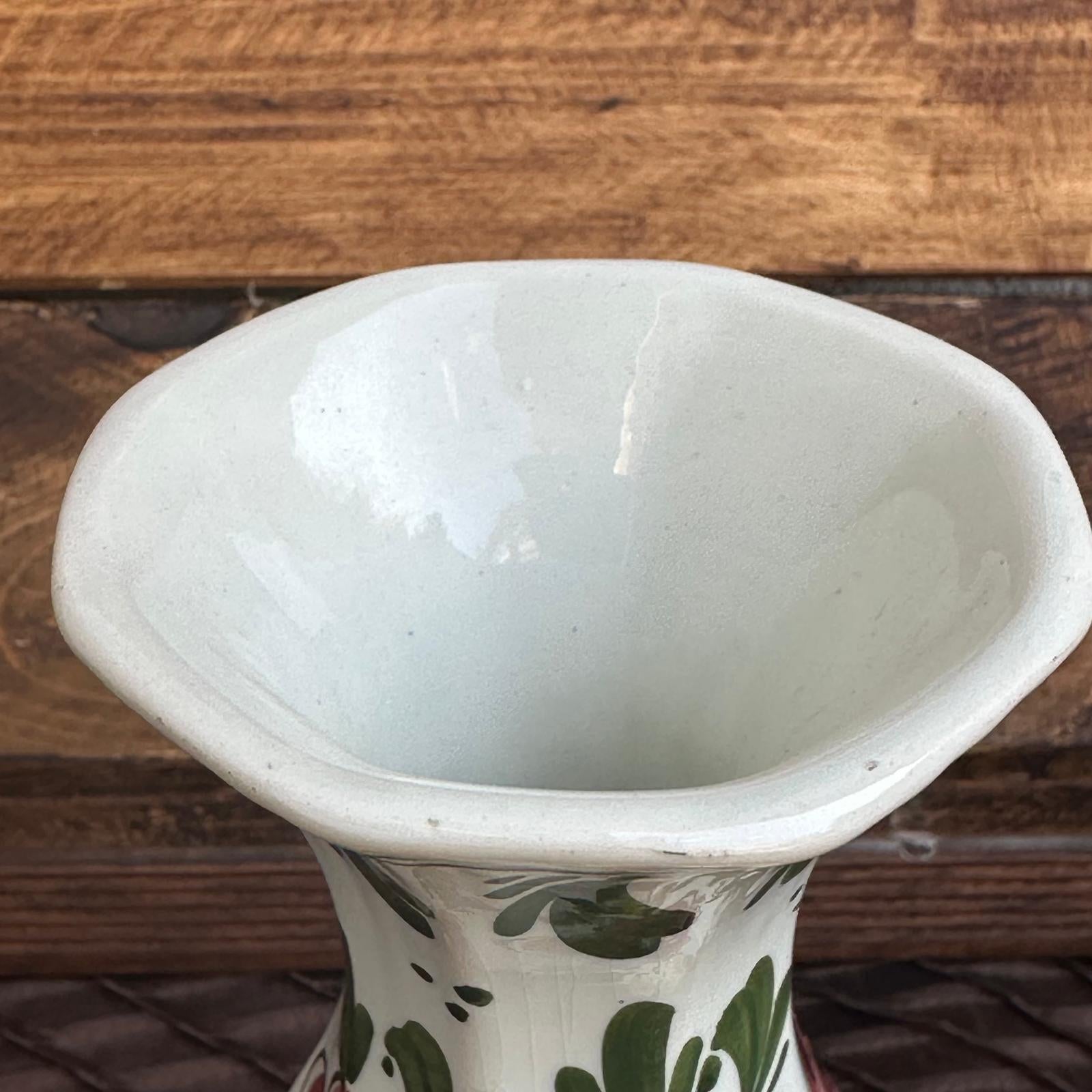 White ceramic vase with green floral patterns on a wooden surface