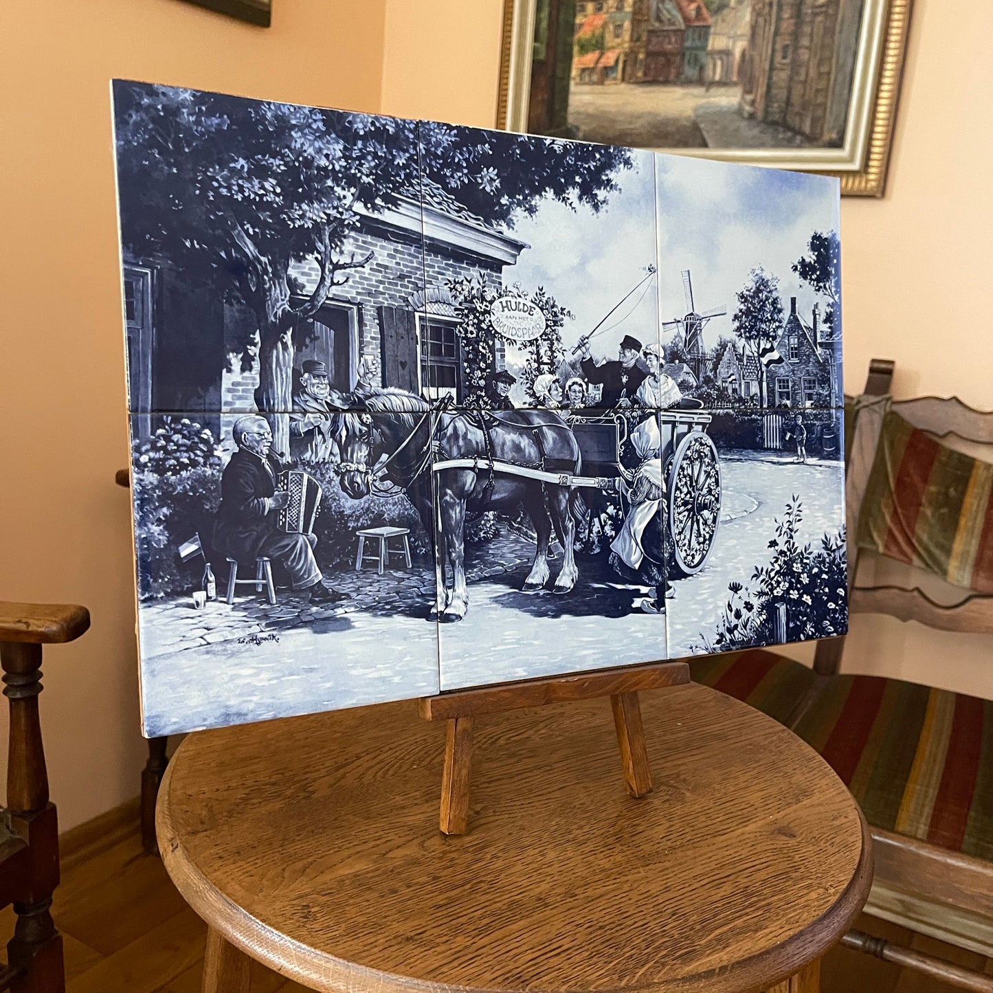 Vintage-style painting on a wooden easel in a room with a couch and framed picture.