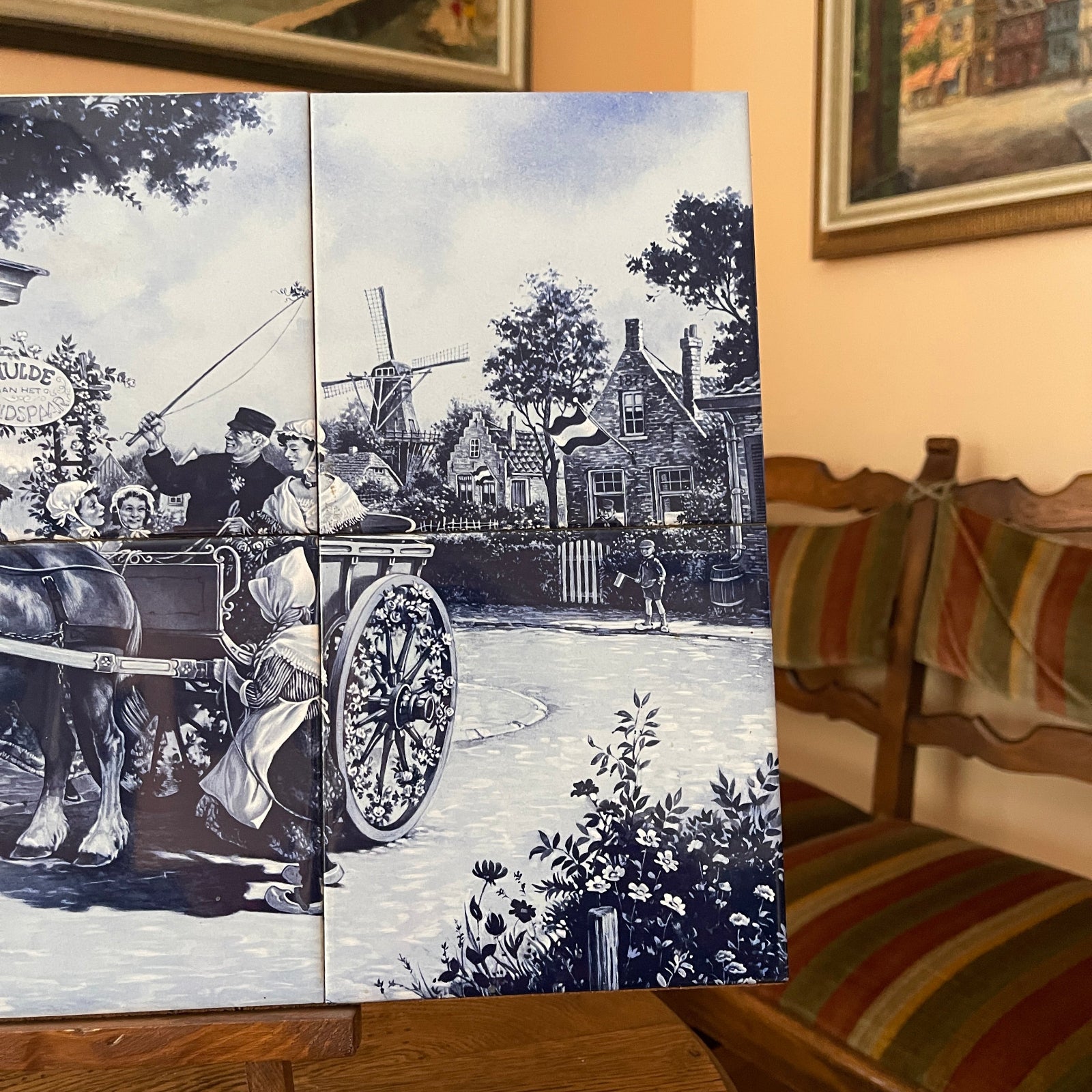 Decorative wall art with a black and white scene of a horse-drawn carriage in a village setting, displayed on a wall.