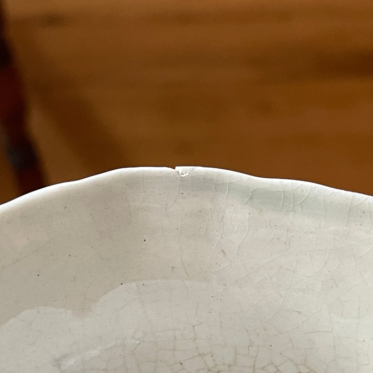Close-up of a textured white ceramic bowl with a blurred brown background