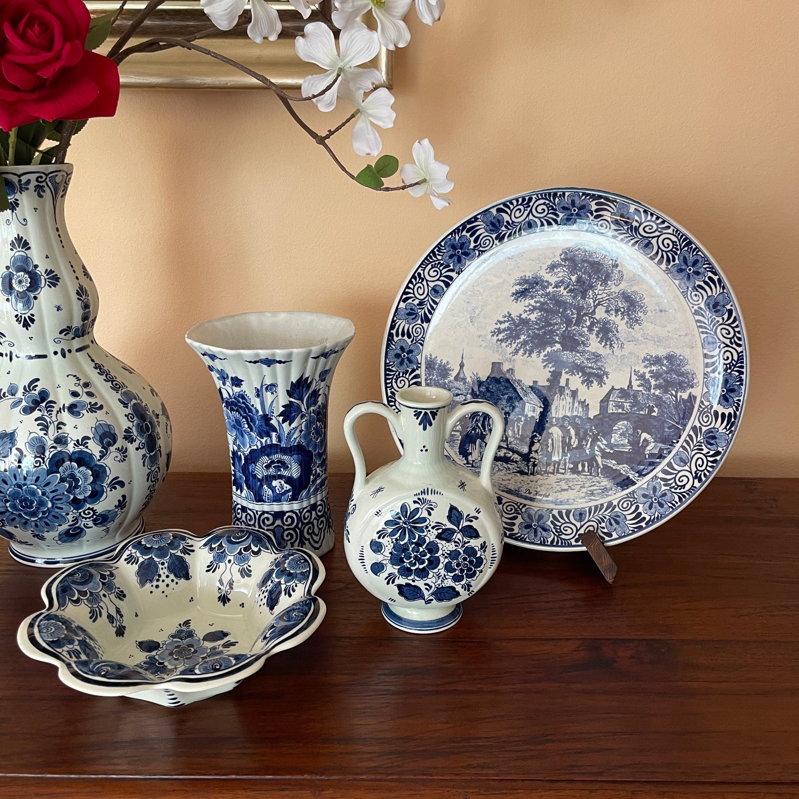 Set of blue and white ceramic items including vases and a plate on a wooden surface.