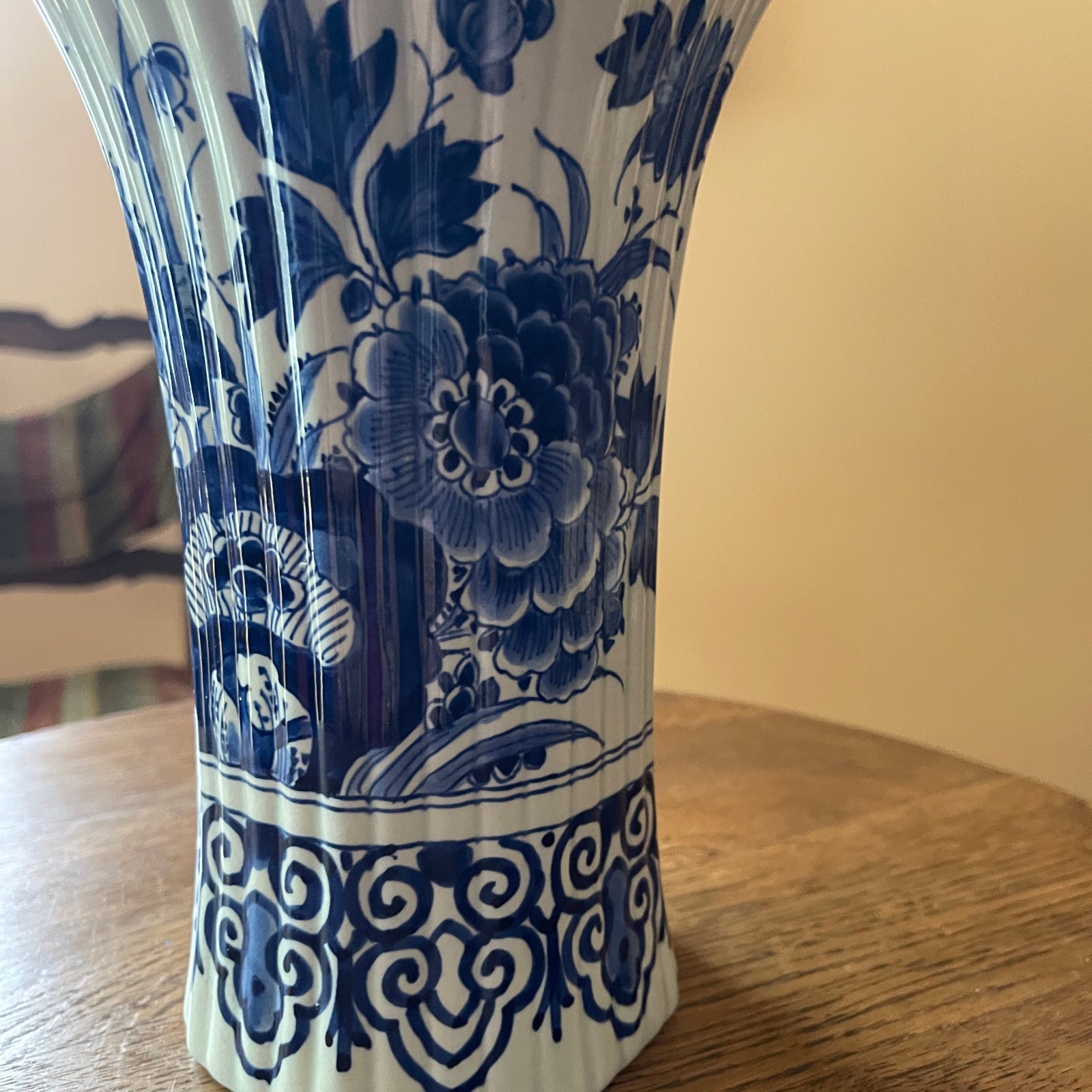 Blue and white floral-patterned vase on a wooden surface with a neutral background