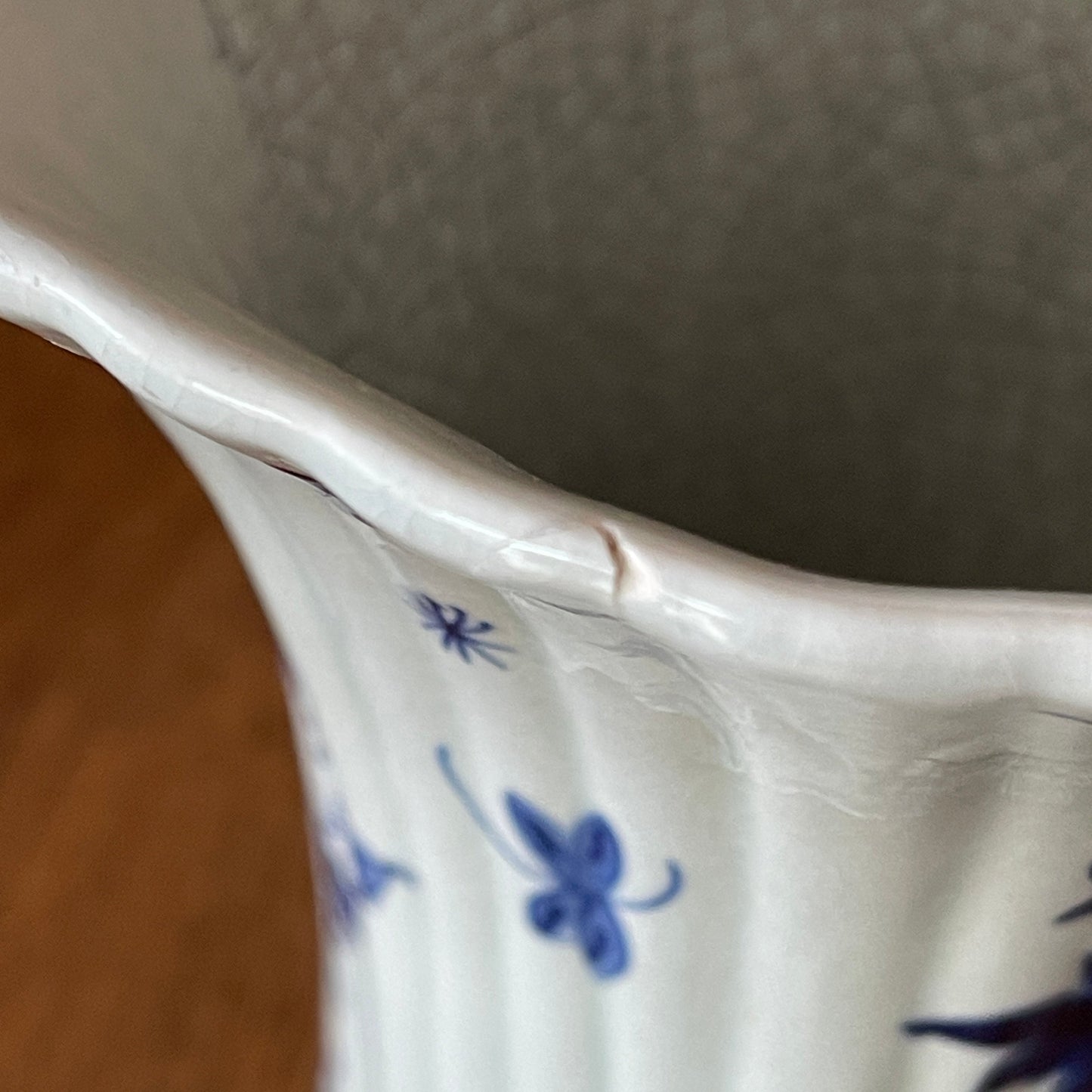 Close-up of a white ceramic vase with blue floral patterns on a neutral background