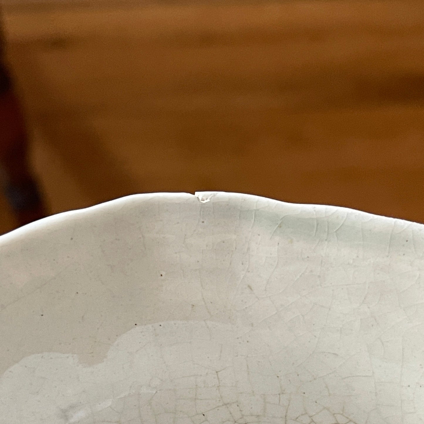 Close-up of a ceramic vase with a textured surface against a blurred brown background
