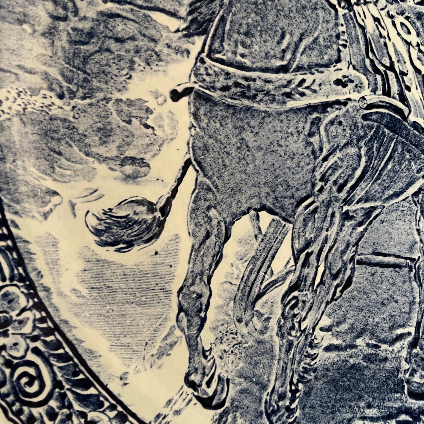 Black and white illustration of a horse and rider on a decorative shield