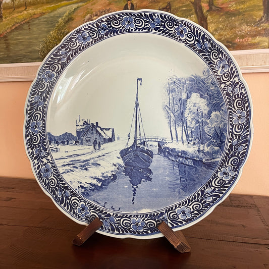 Decorative plate with blue and white landscape design featuring a boat and house.