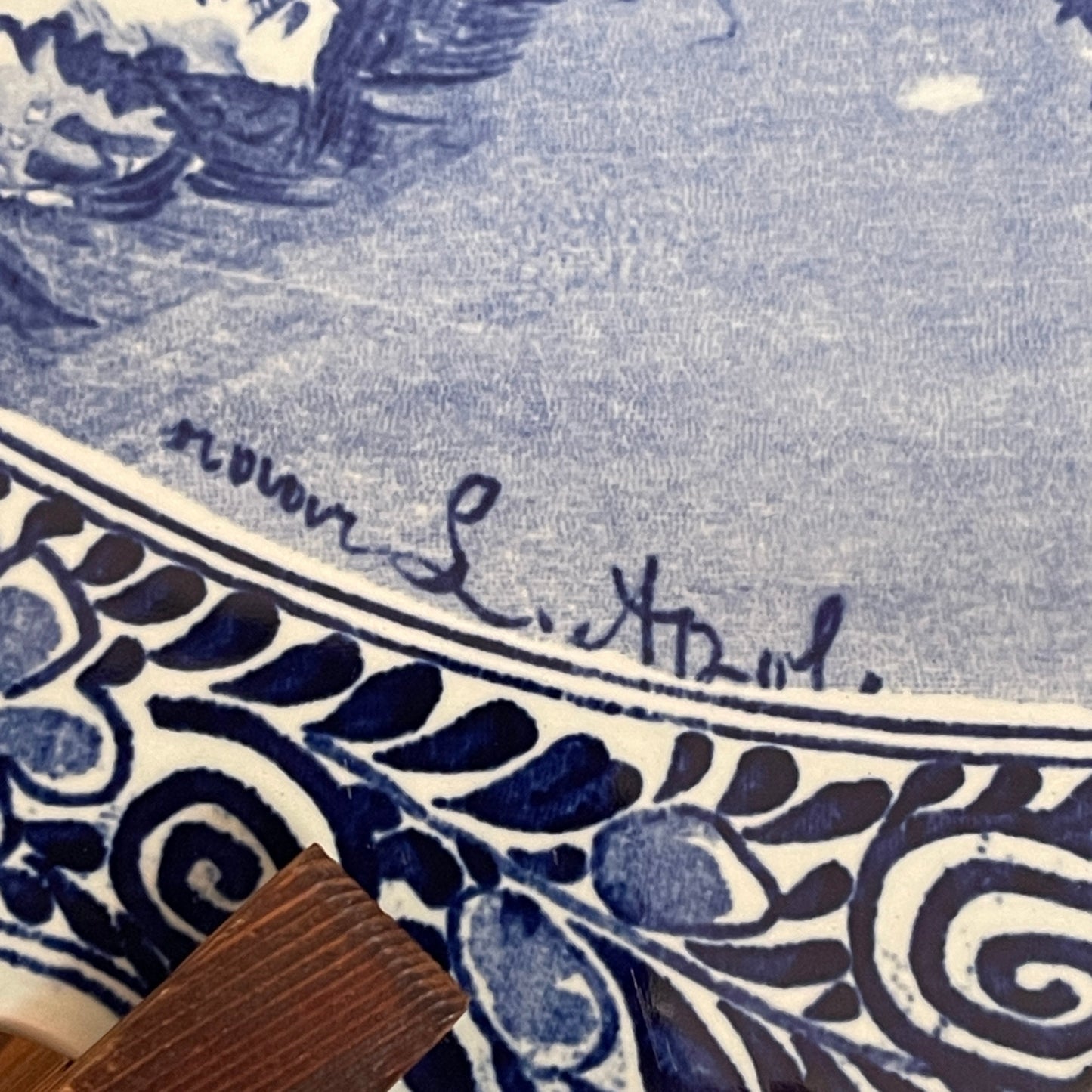 Close-up of a blue and white patterned fabric with a signature at the bottom right corner.