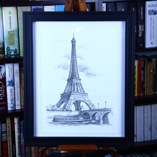 Framed print of the Eiffel Tower overlooking the Seine, drawn in pencil and signed by Arben, displayed on a stand with a black frame.