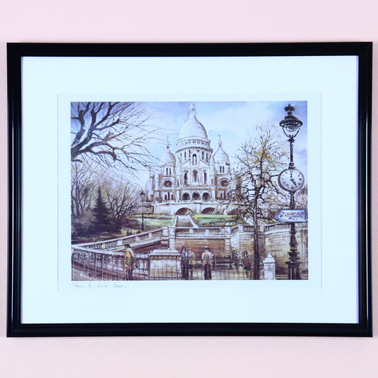 Framed print of the Sacre-Coeur in Paris, featuring the basilica and surrounding area, set in a black frame.