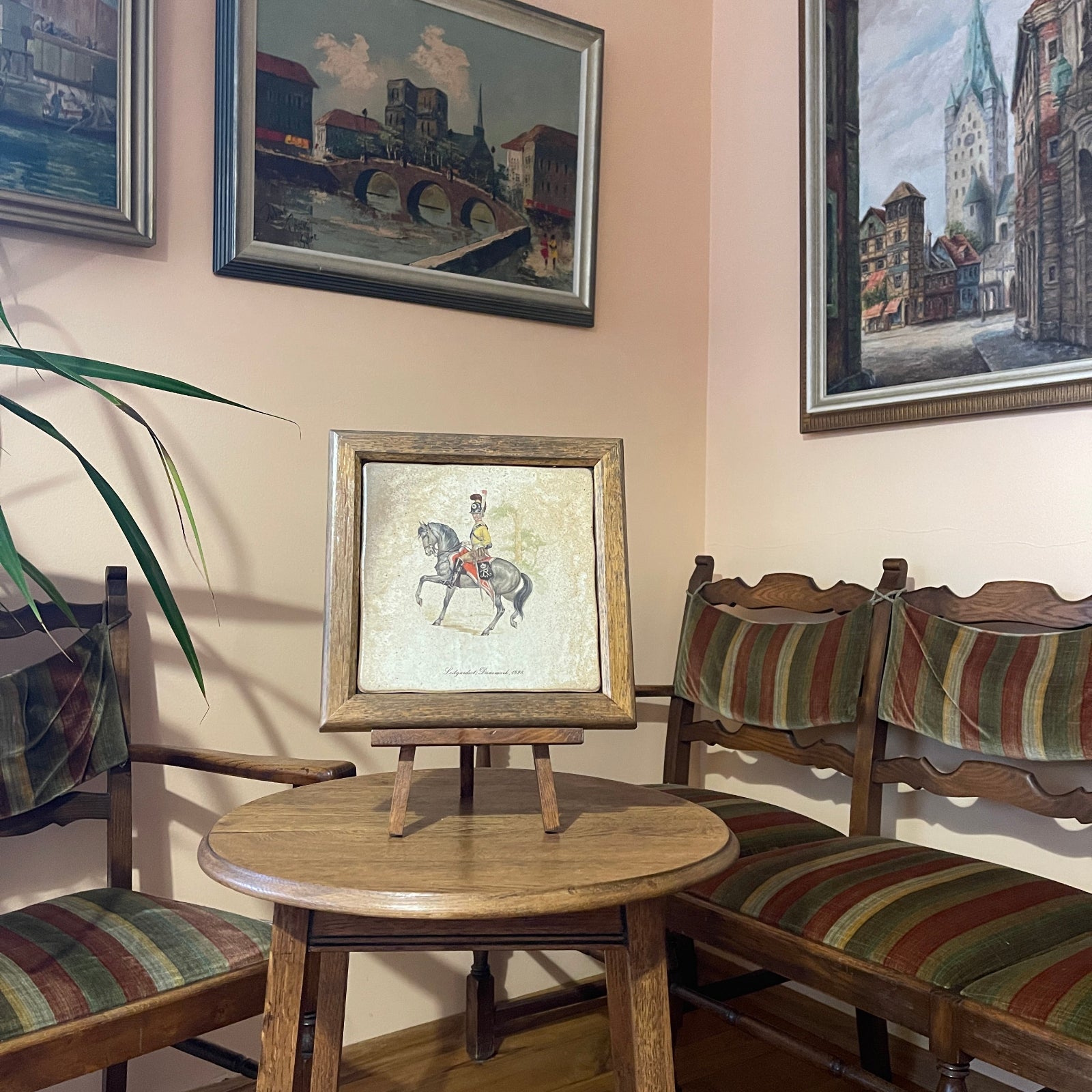 Room interior with wooden chairs, a small round table, and framed pictures on the wall.