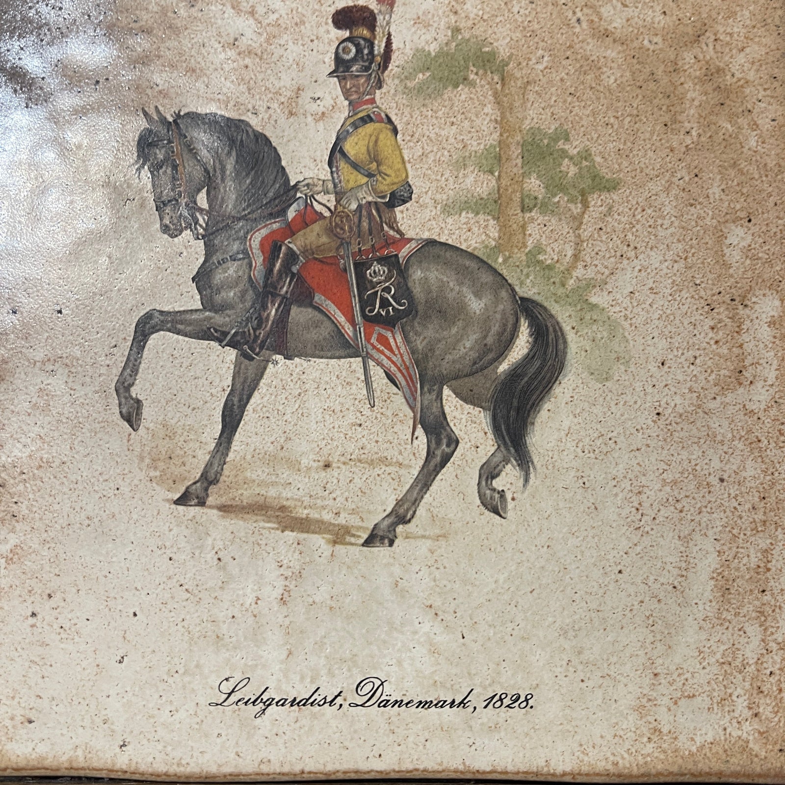 Painting of a soldier on horseback with a decorative saddle, dated 1828, on a textured beige background.