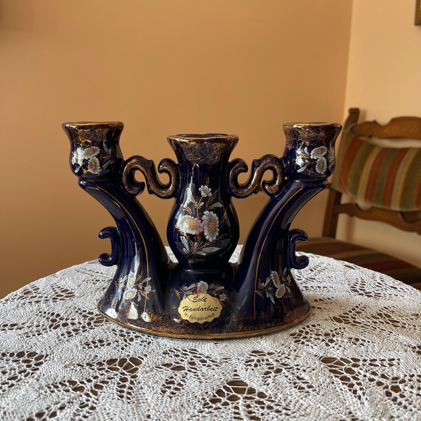 Decorative black vase with floral patterns on a lace tablecloth