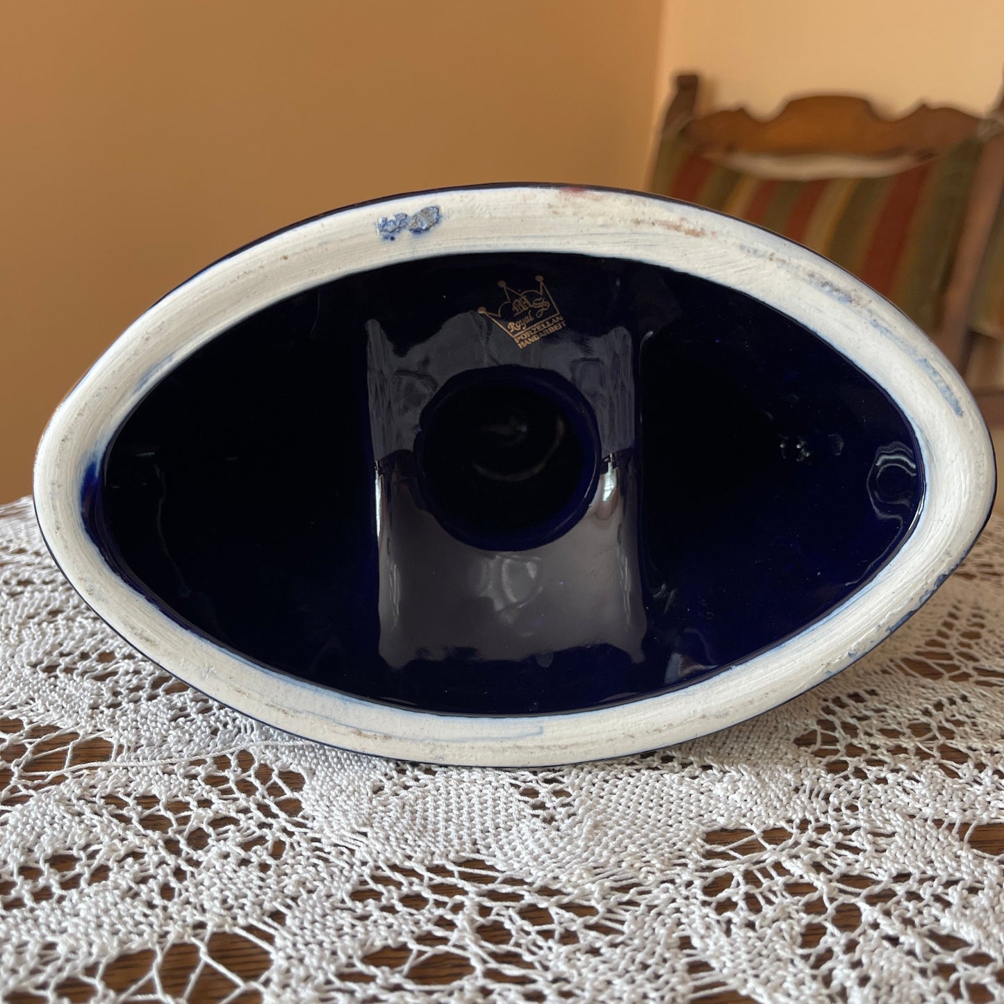 Blue ceramic dish on a lace tablecloth with a wooden chair in the background