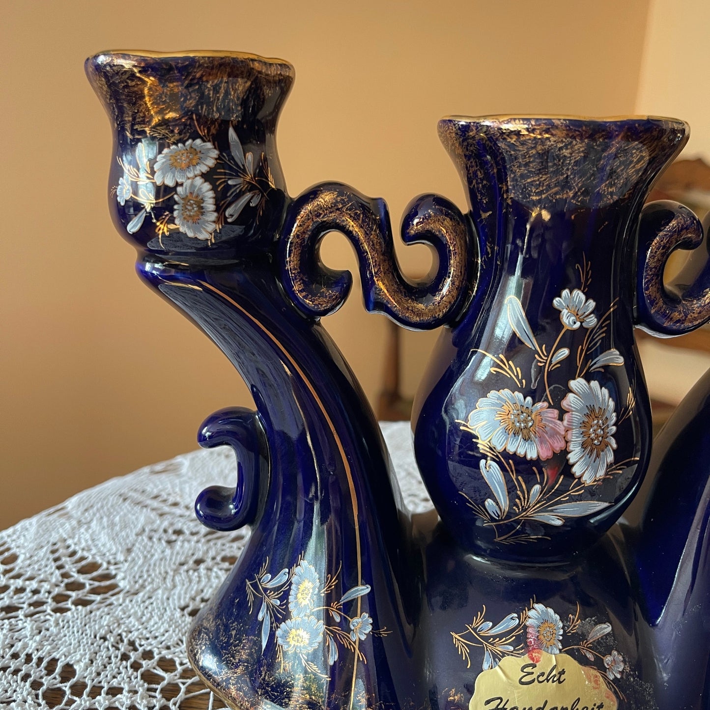 Two decorative blue vases with floral patterns on a lace tablecloth.