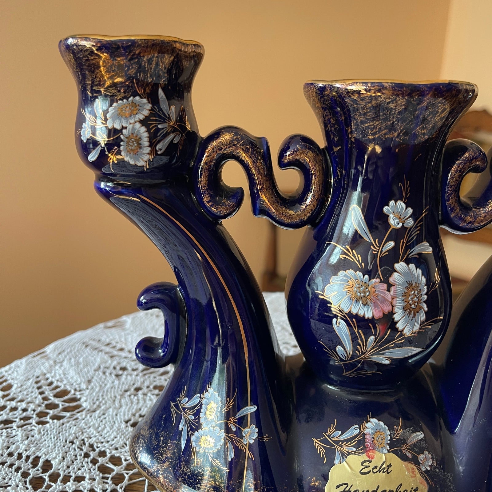 Two decorative blue vases with floral patterns on a lace tablecloth.
