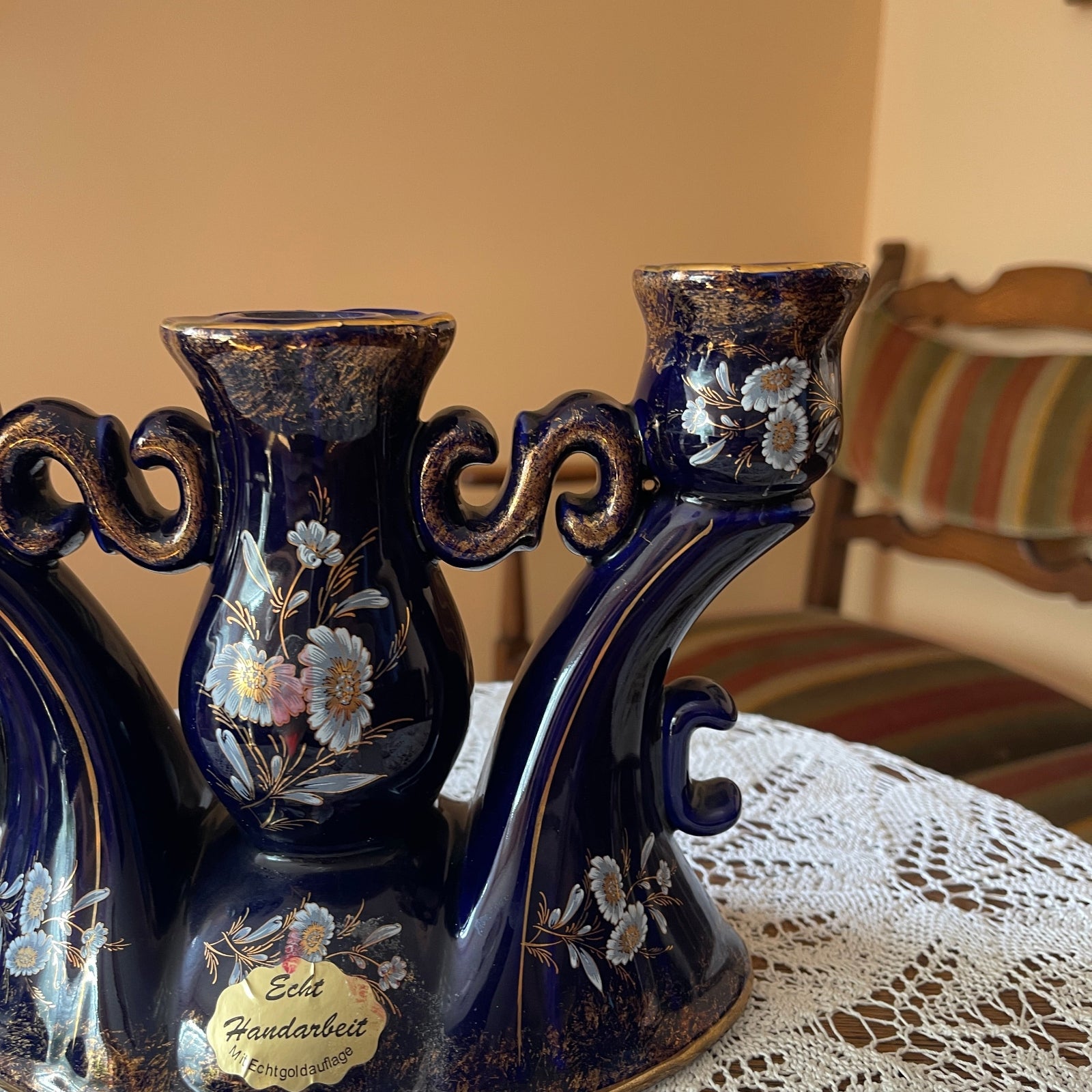 Decorative blue candlestick holders with floral designs on a lace tablecloth.