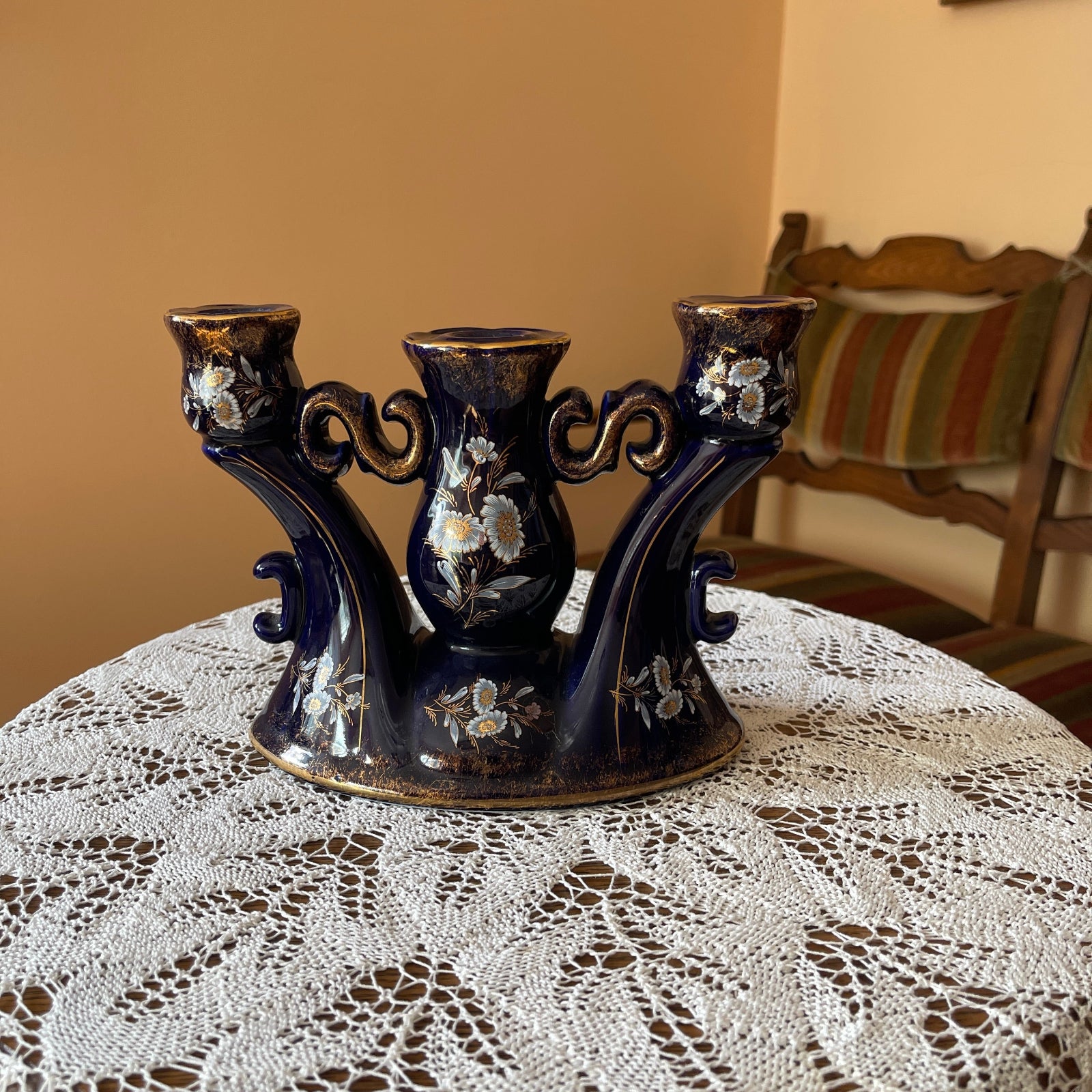 Decorative black candle holder with floral designs on a lace tablecloth.