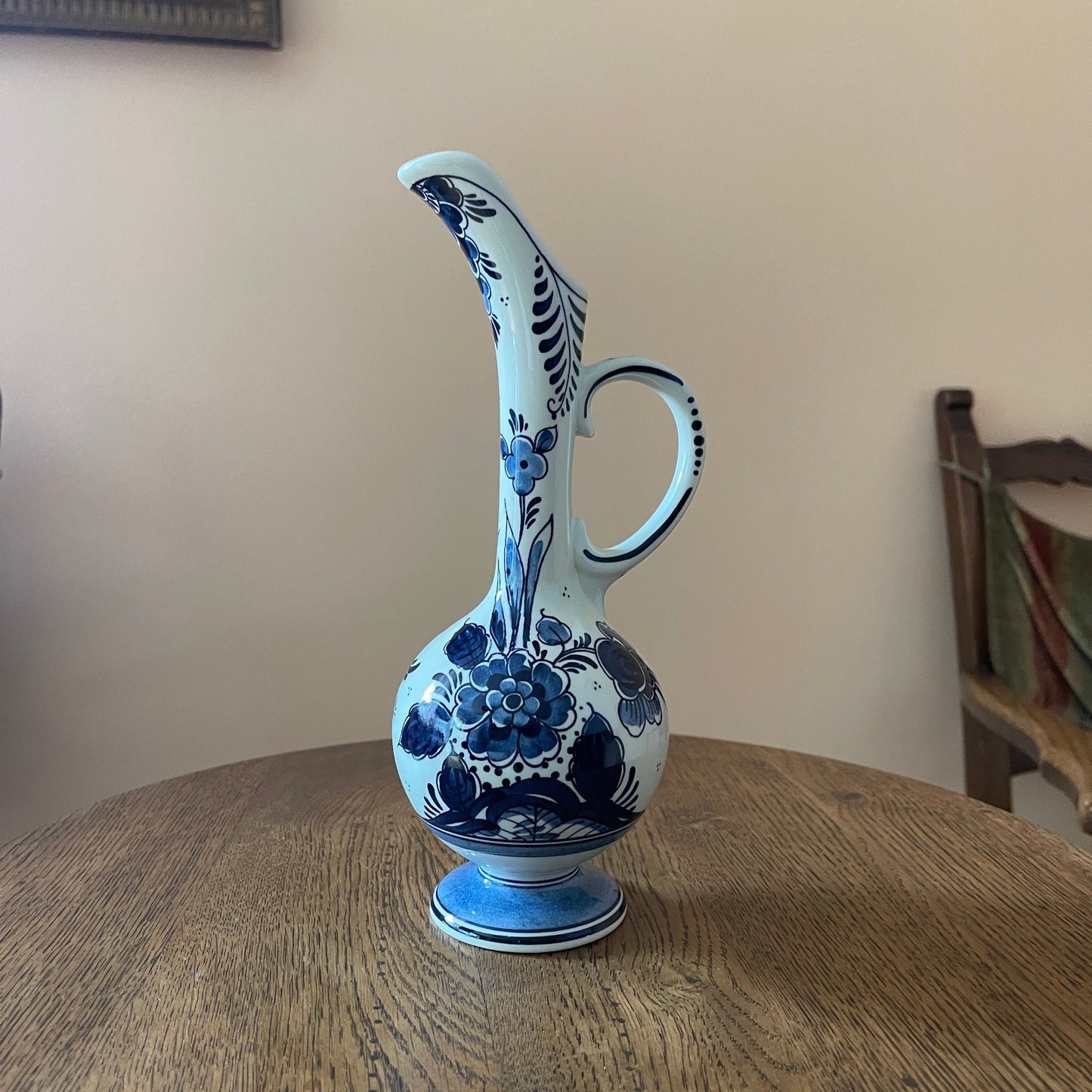 Blue and white floral-patterned ceramic pitcher on a wooden surface with a neutral background