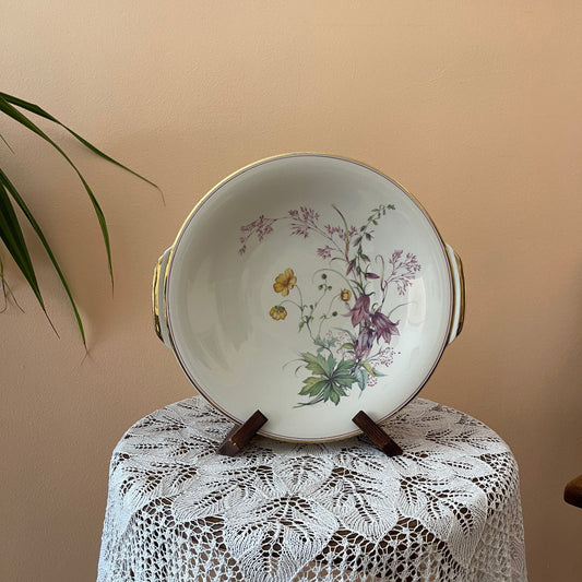Decorative plate with floral design on a stand against a beige wall