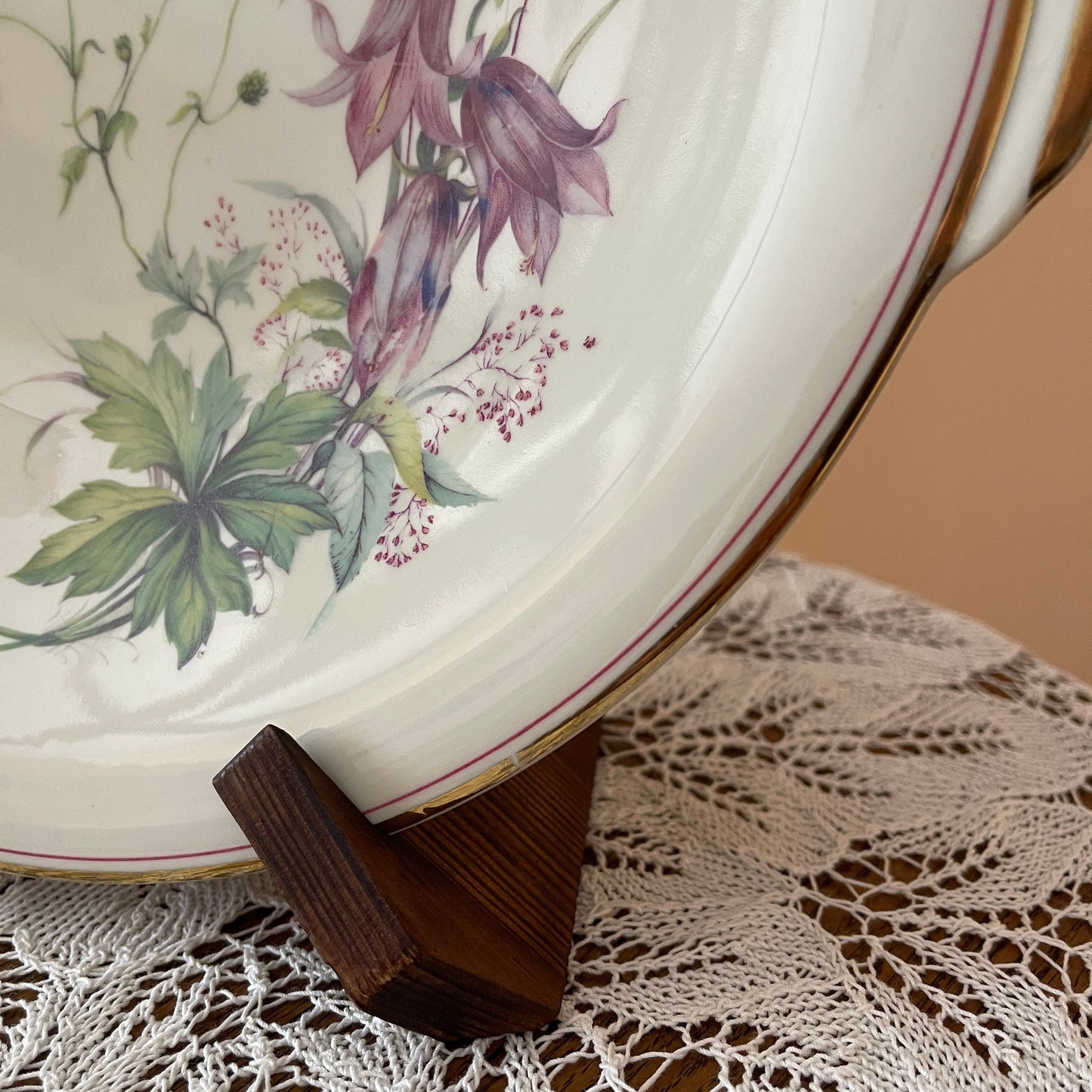 Floral-patterned plate on a wooden stand with a lace tablecloth