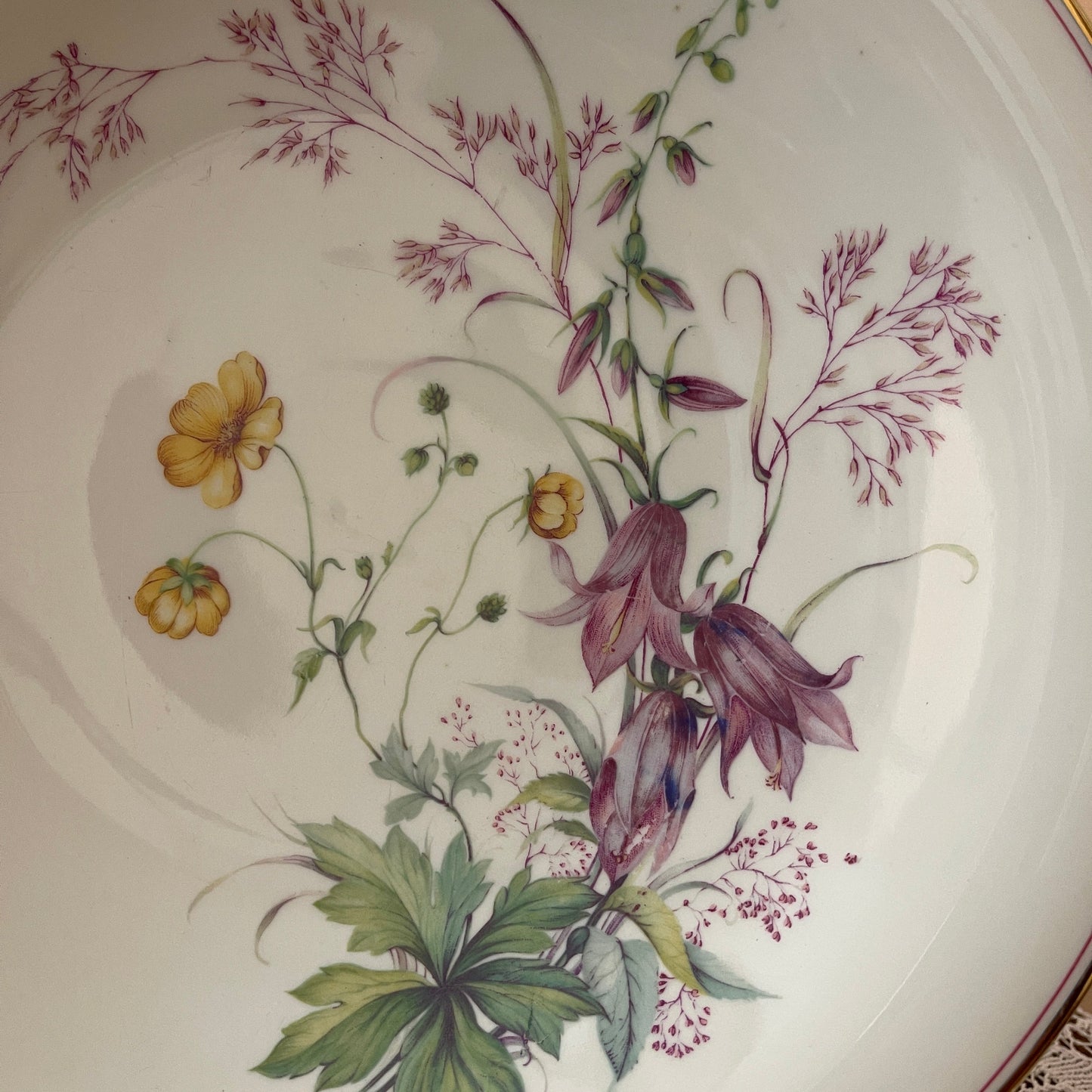 Decorative plate with floral design featuring purple and yellow flowers on a white background