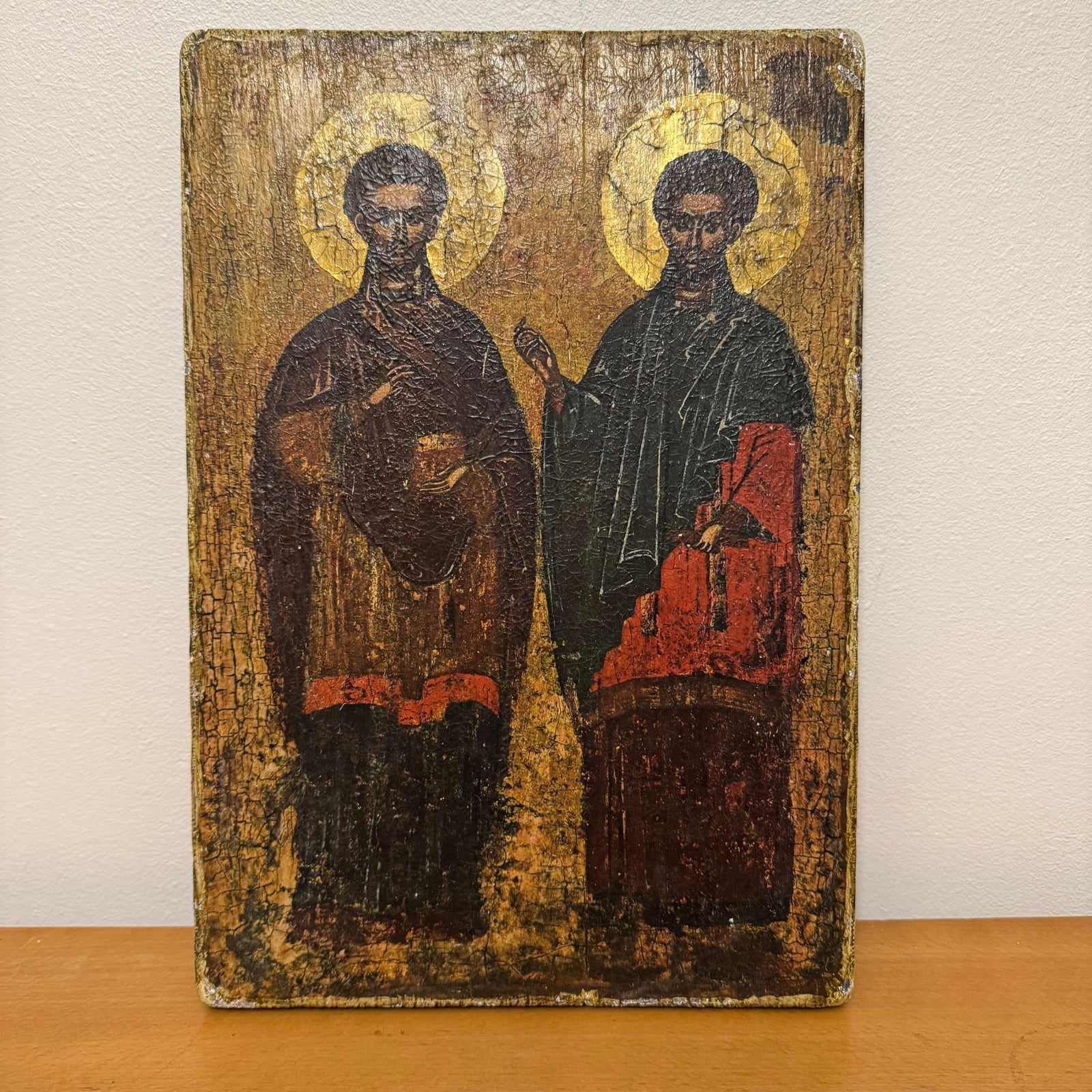 Vintage icon of two figures with halos on a wooden surface