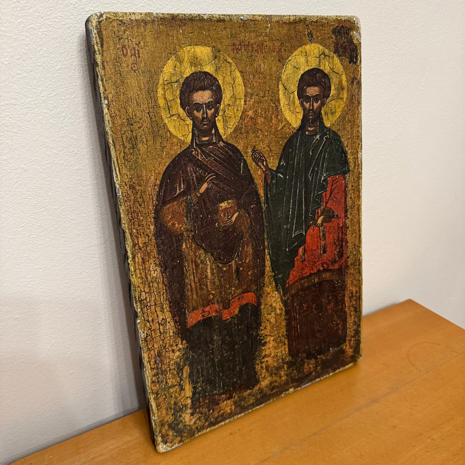 Vintage icon with two figures on a wooden surface against a white wall