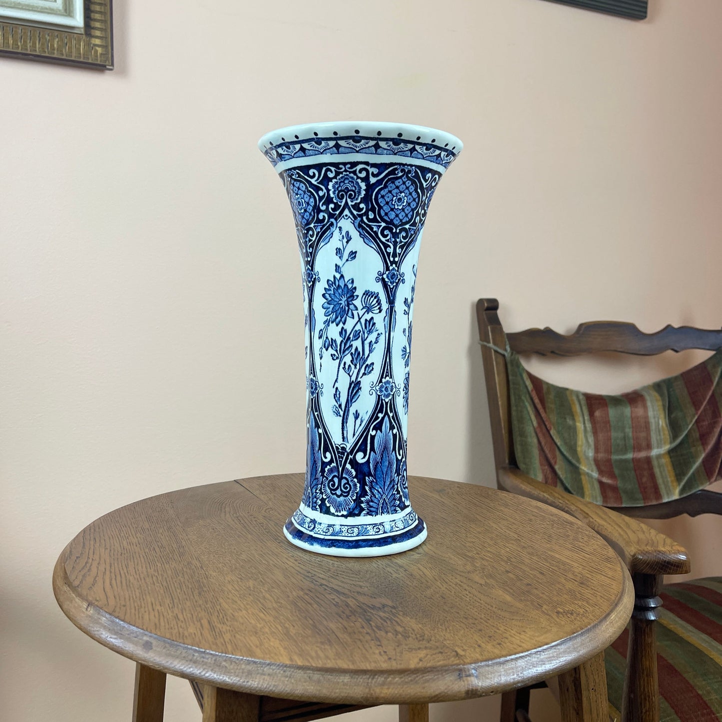Blue and white ceramic vase on a wooden table with a chair in the background