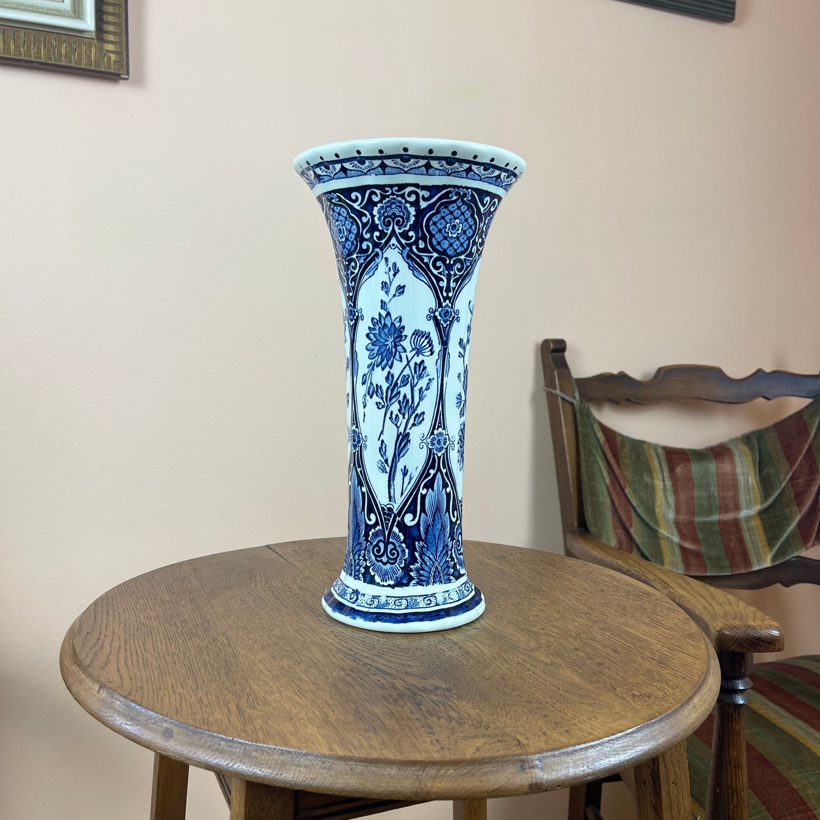 Blue and white ceramic vase on a wooden table with a chair in the background