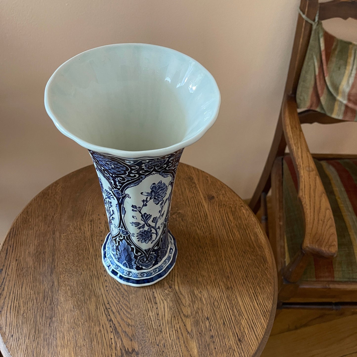 Blue and white vase on a wooden table with a chair in the background