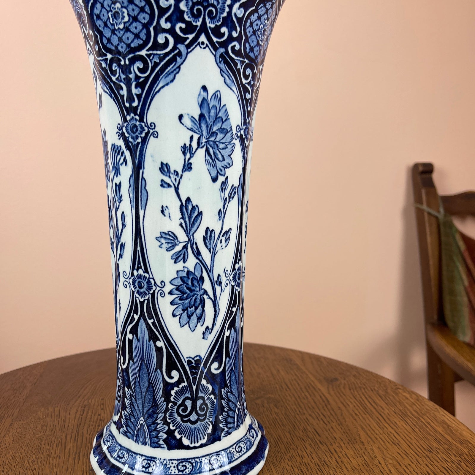 Blue and white floral-patterned vase on a wooden surface with a neutral background