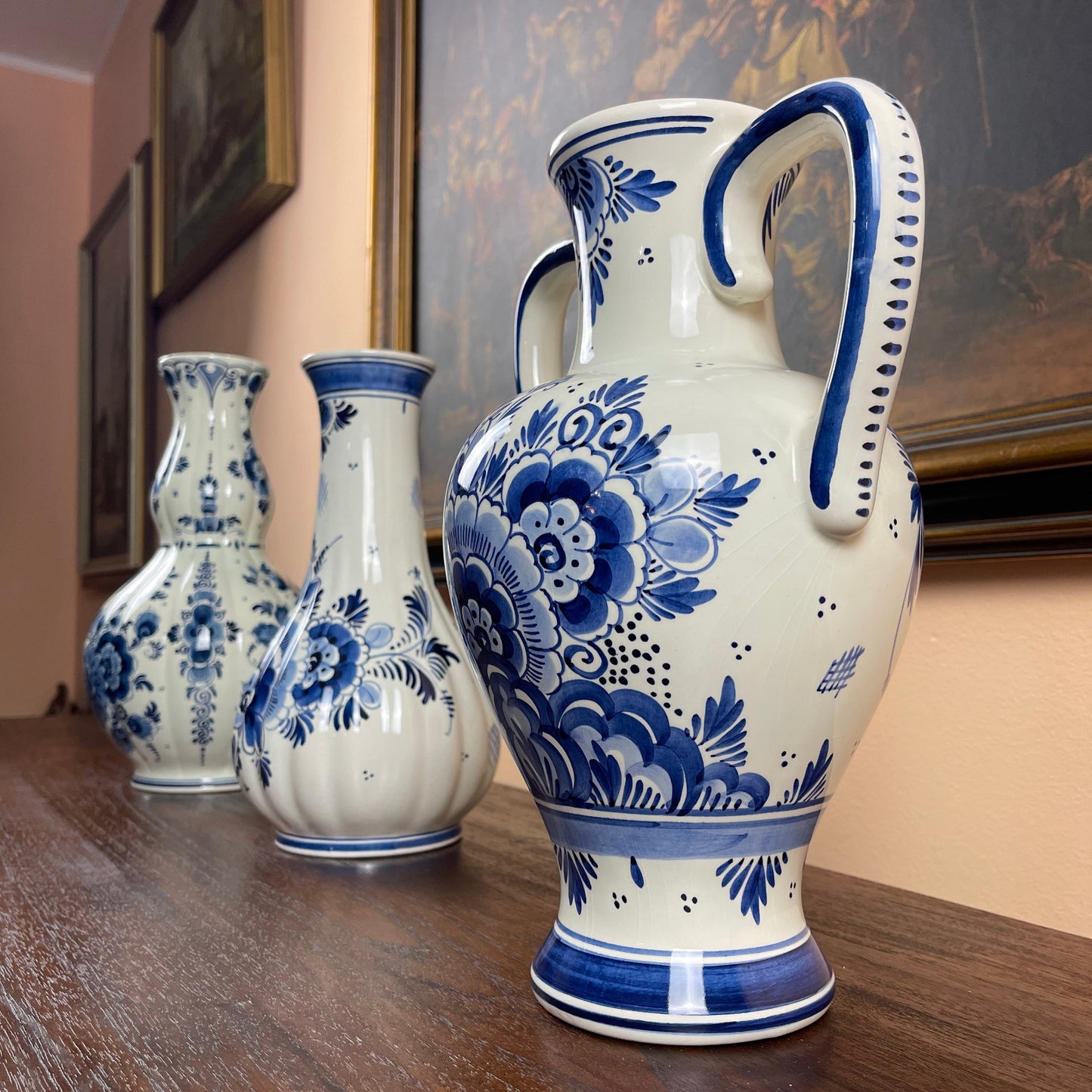 Set of three white vases with blue floral patterns on a wooden surface.