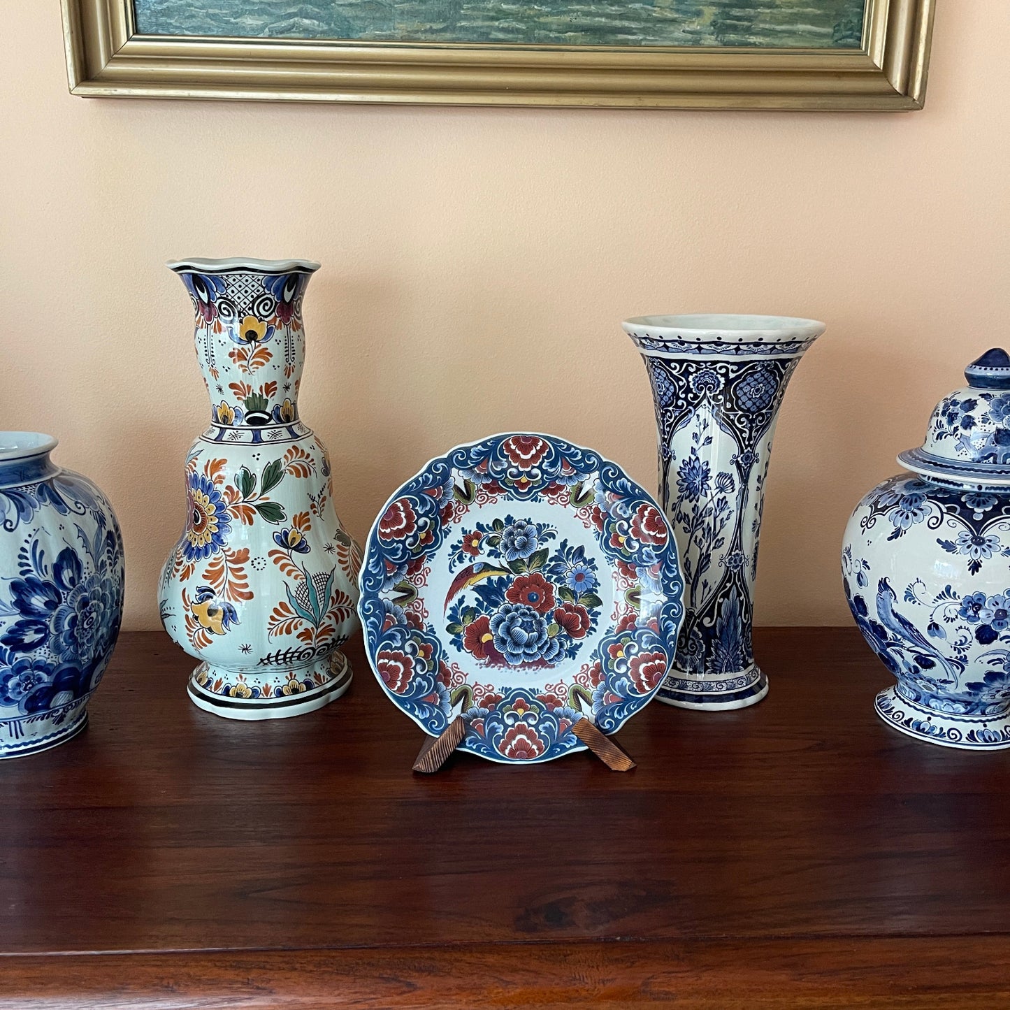 Collection of decorative ceramic vases and a plate with floral patterns on a wooden surface.