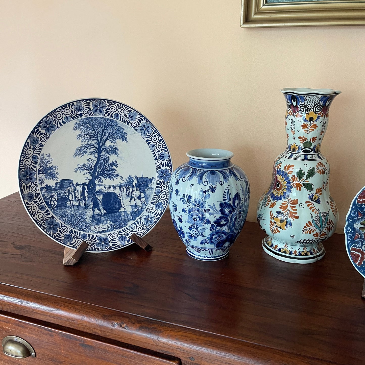 Decorative ceramic items including a plate, two vases, and a small bowl on a wooden surface.