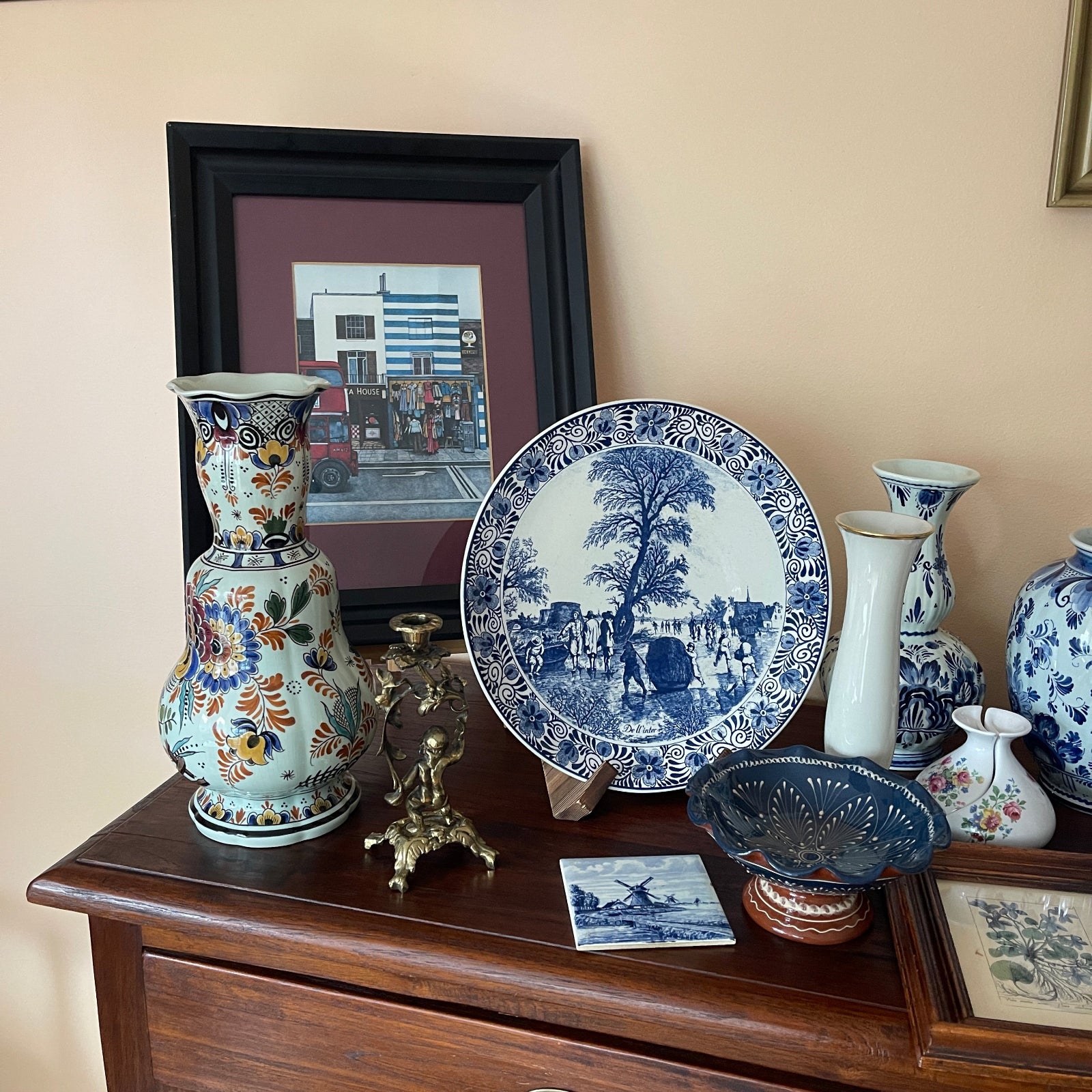 Decorative items including vases and a plate on a wooden surface with a framed picture in the background.