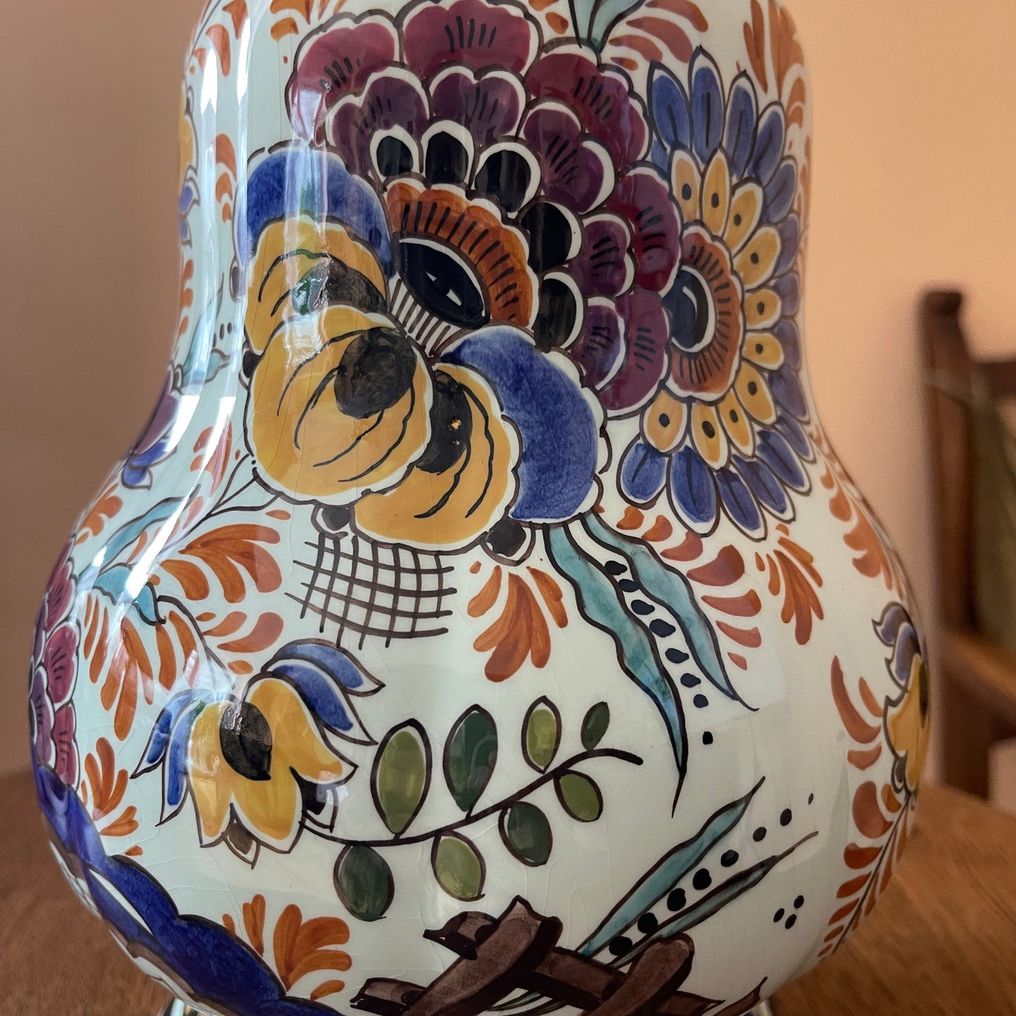 Ceramic vase with colorful floral patterns on a wooden surface.