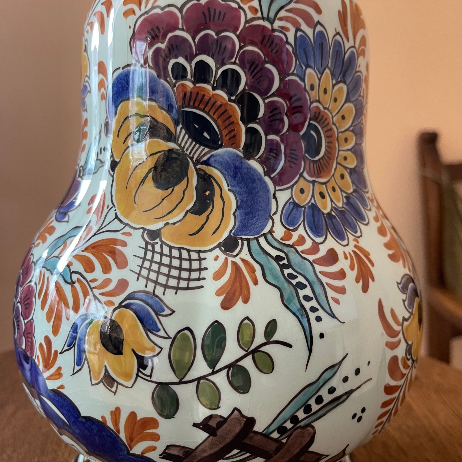 Ceramic vase with colorful floral patterns on a wooden surface.
