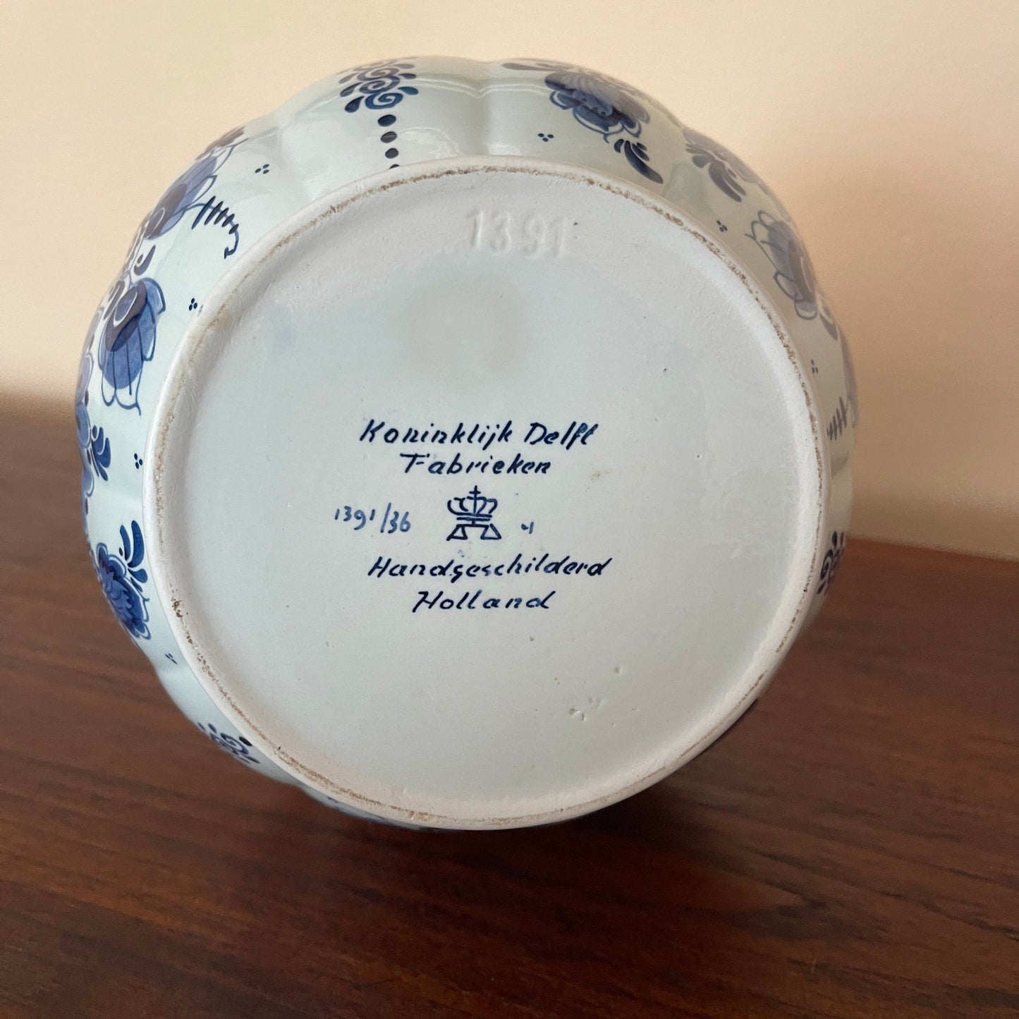 Ceramic vase with blue floral patterns and 'Koninklijk Delft Fabrieken' branding on a wooden surface.