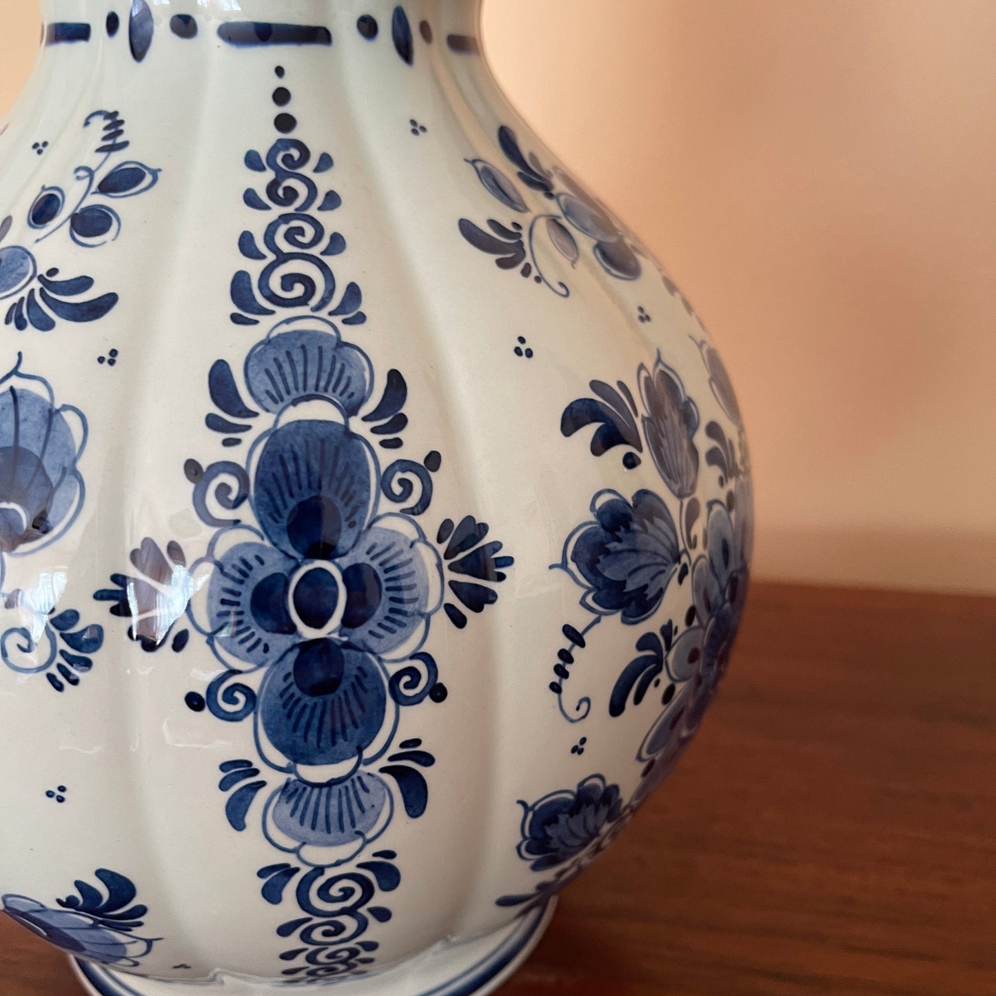 White ceramic vase with blue floral patterns on a wooden surface.